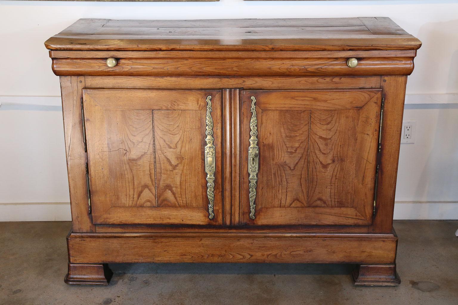 A beautiful antique French buffet featuring one drawer and two lower doors with brass hardware and key. As seen in the photos, the escutcheons depict Christ on the Cross and two Angels praying beneath Him, this leads us to believe the piece was