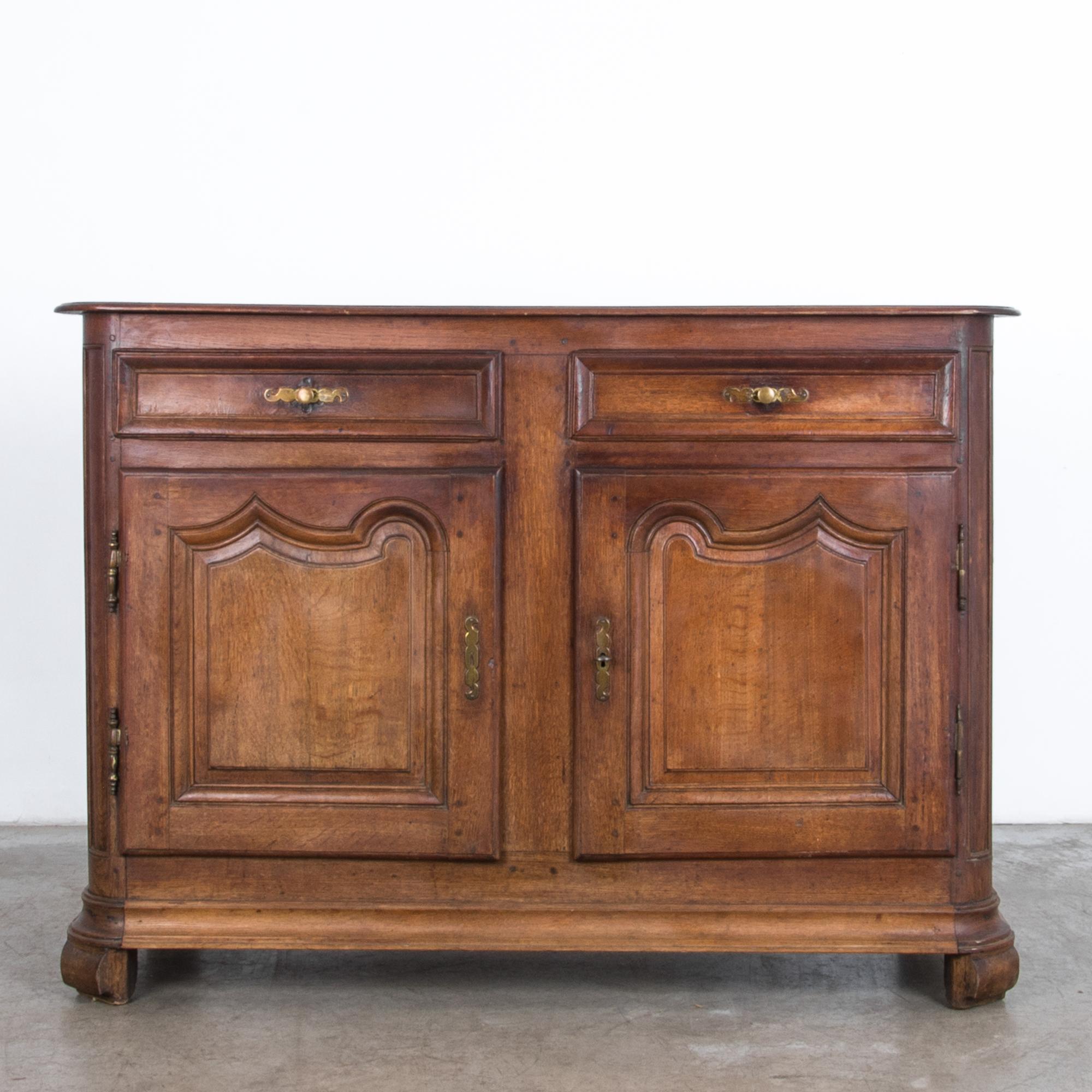 From circa 1800, a two-door and drawer cabinet in oak. A distinct approach typifies the casual yet refined aesthetic of the French countryside. Repolished through the ages, the warm translucent color enhances the texture of age and material, a