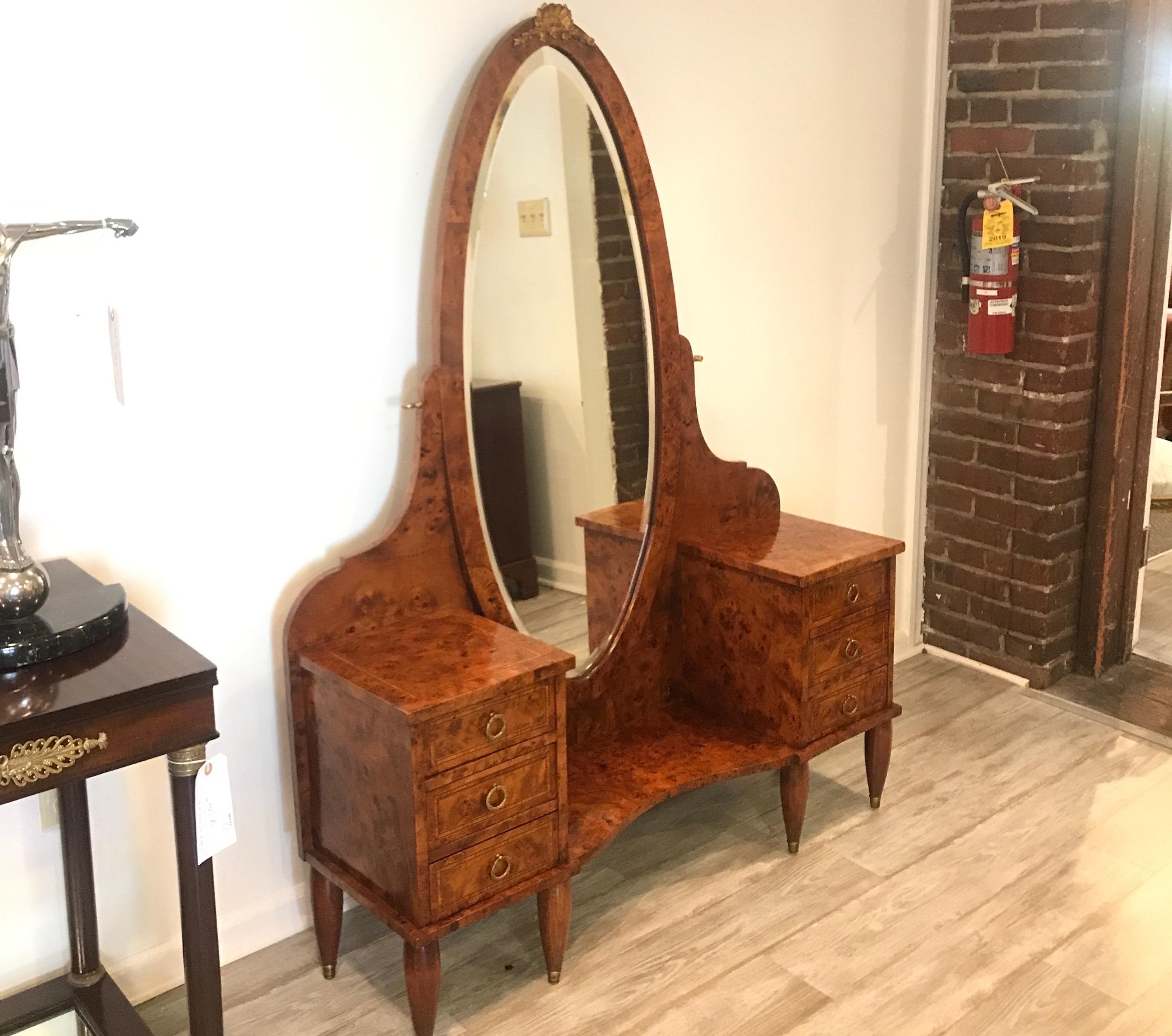 Graceful French burled walnut vanity with dramatic beveled oval mirror. Three drawers on each side with gilt bronze ring handles. The beveled mirror with ormolu mount on top which tilts.