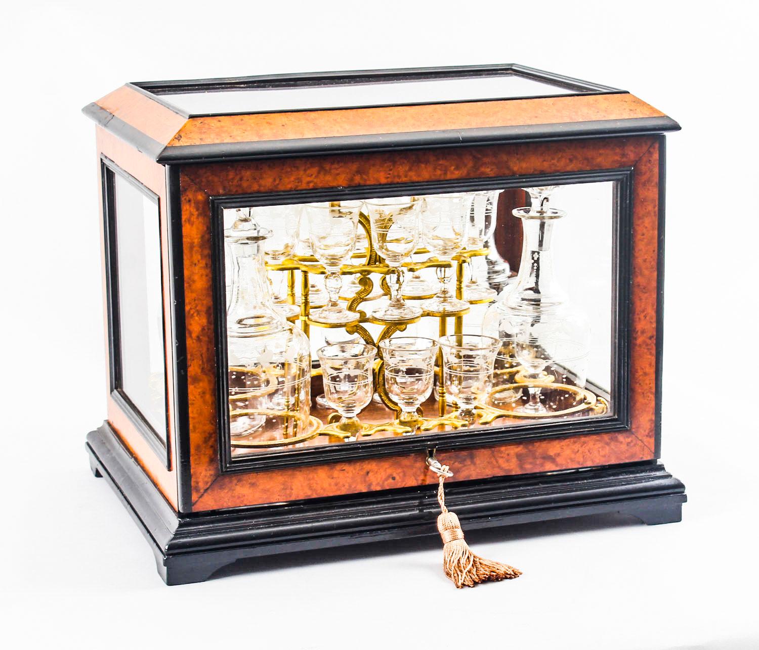 This is an exquisite antique French burr-walnut and ebonized cave a liqueur, or tantalus, circa 1860 in date. 
 
The cave a liqueur features a burr walnut and ebonized case with glass panels and an 'up and over' lid enclosing a gilt bronze frame
