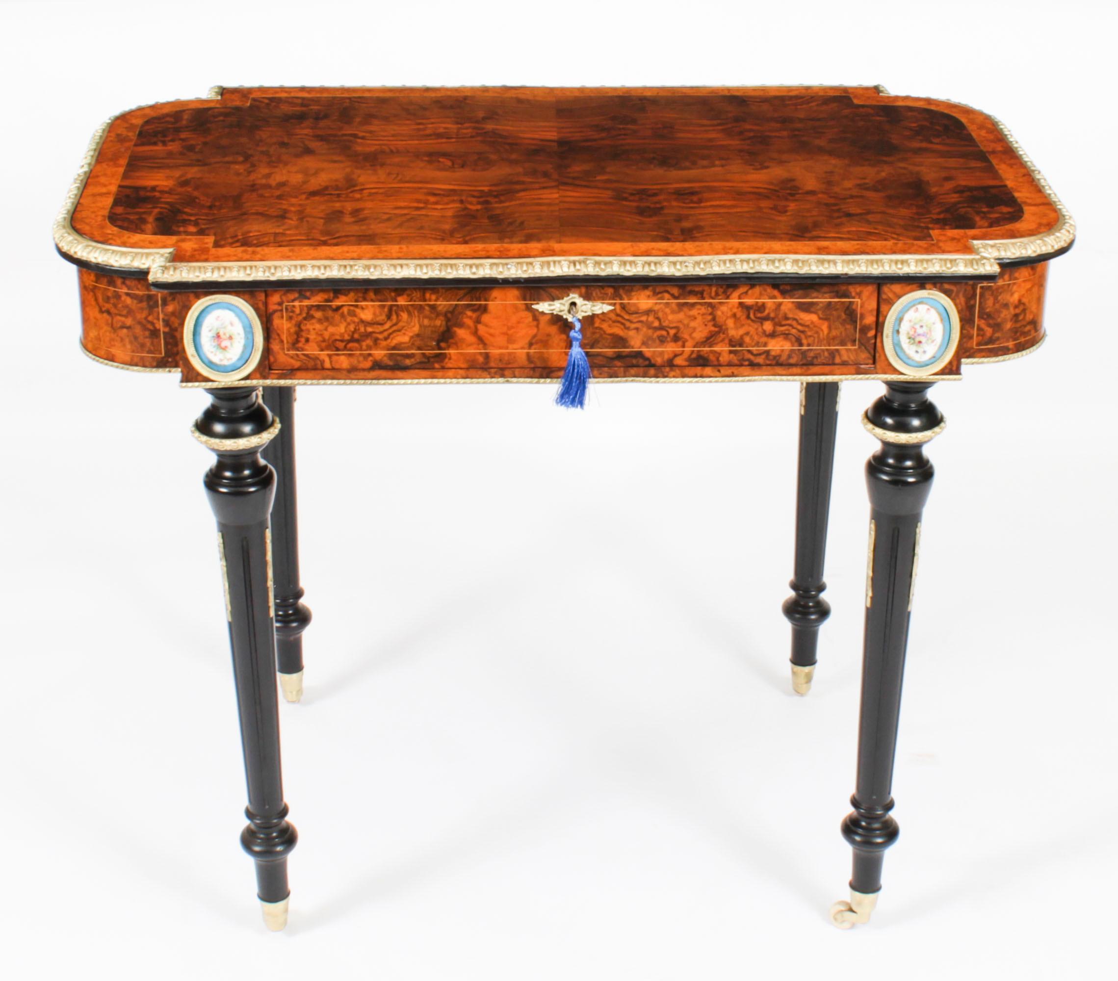This is an elegant antique French ormolu mounted burr walnut writing table, Circa 1870 in date.
 
This lovely shaped top is crafted from the most beautiful burr walnut, with amboyna crossbanded decoration and boxwood stringing, and featuring a