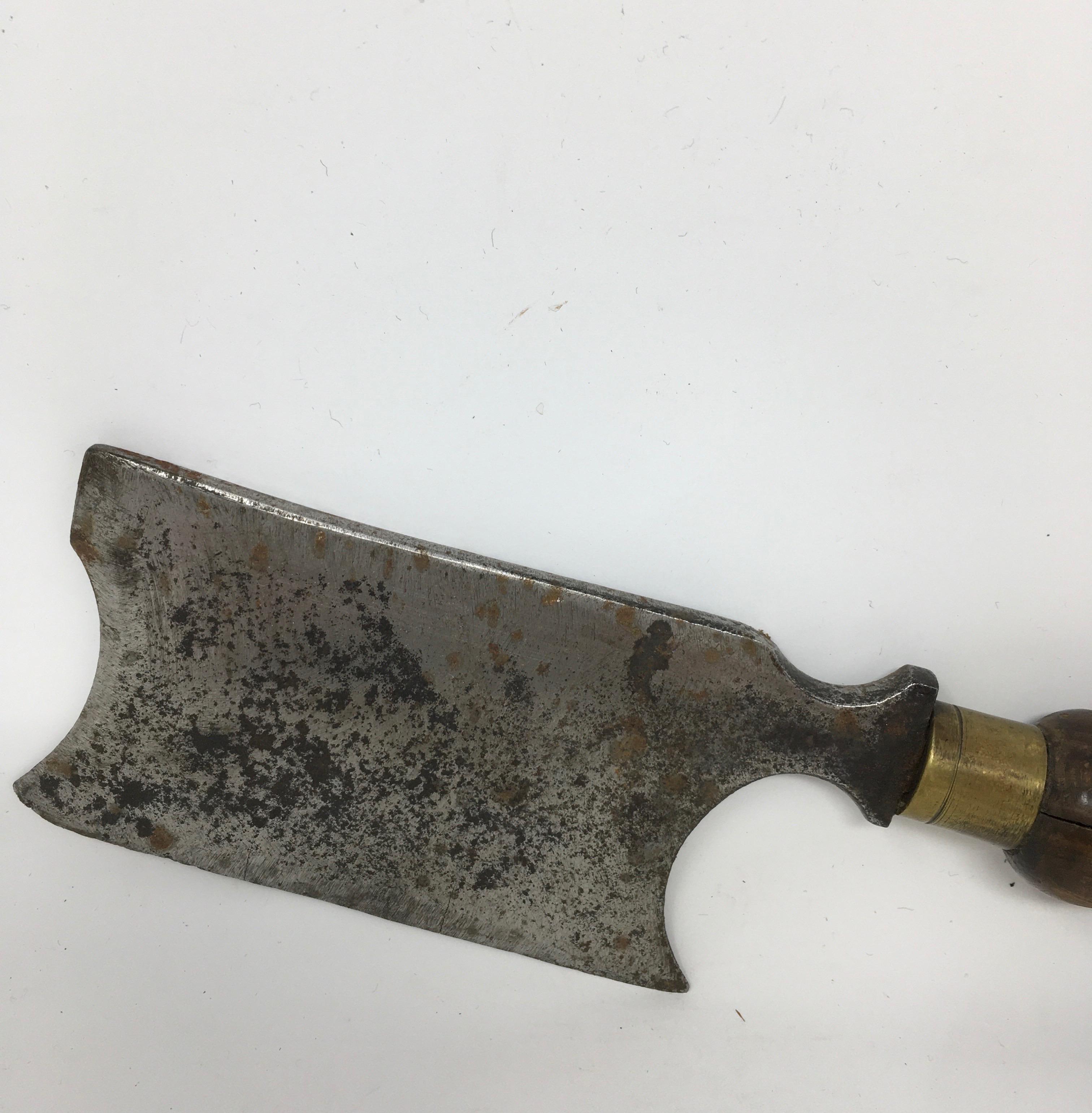 This is an antique butcher's cleaver from France. The blade is made of heavy steel, the handle is wood and brass. Once used by a butcher in a boucherie, this piece is sure to add charm to your kitchen.