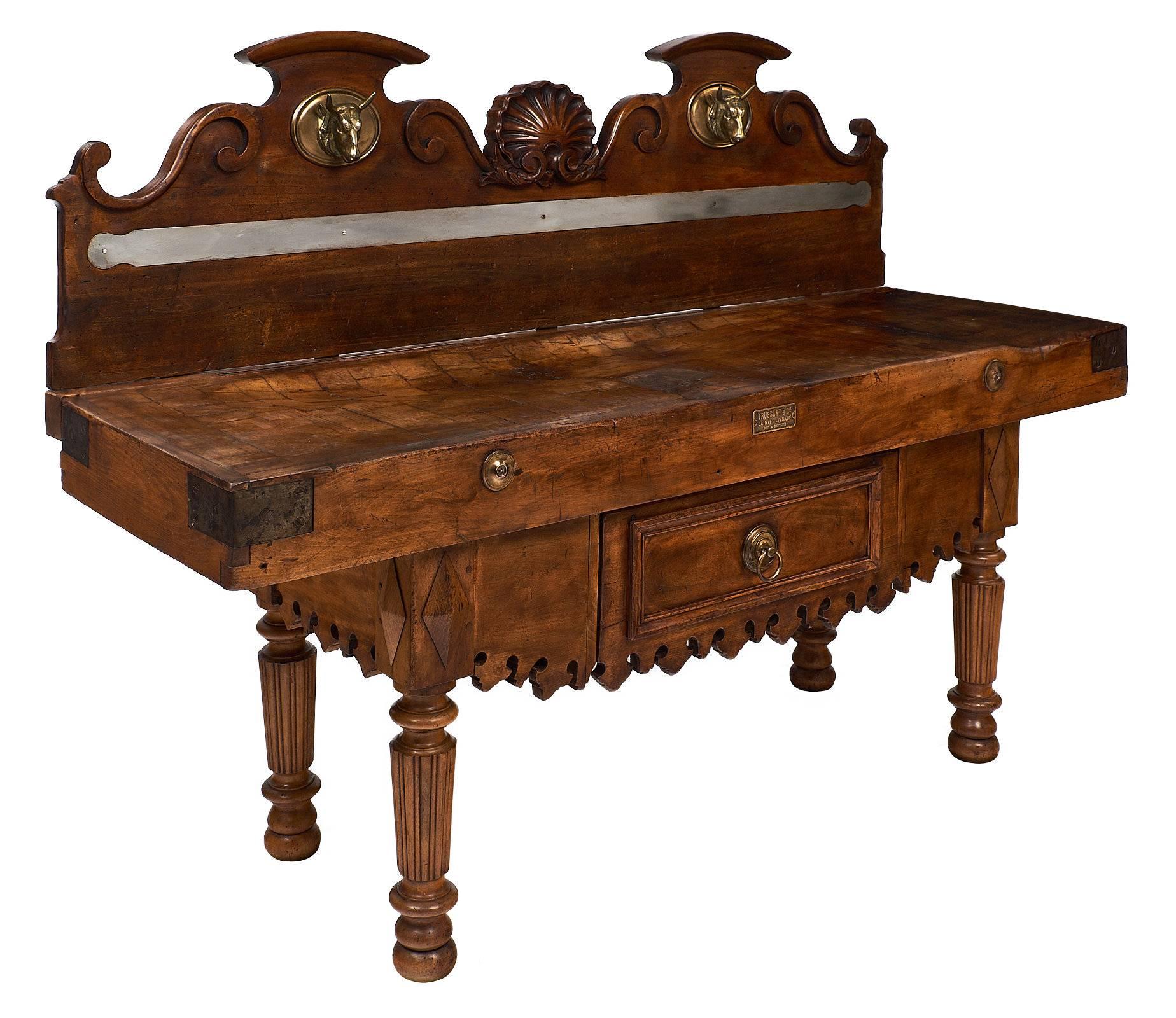 From Vienne in The Rhone Valley, this spectacular French antique butcher table has the original decor boasting bronze finely cast cow heads flanking a hand carved scallop. The knife holder is in place and the working slab is trimmed with steel on