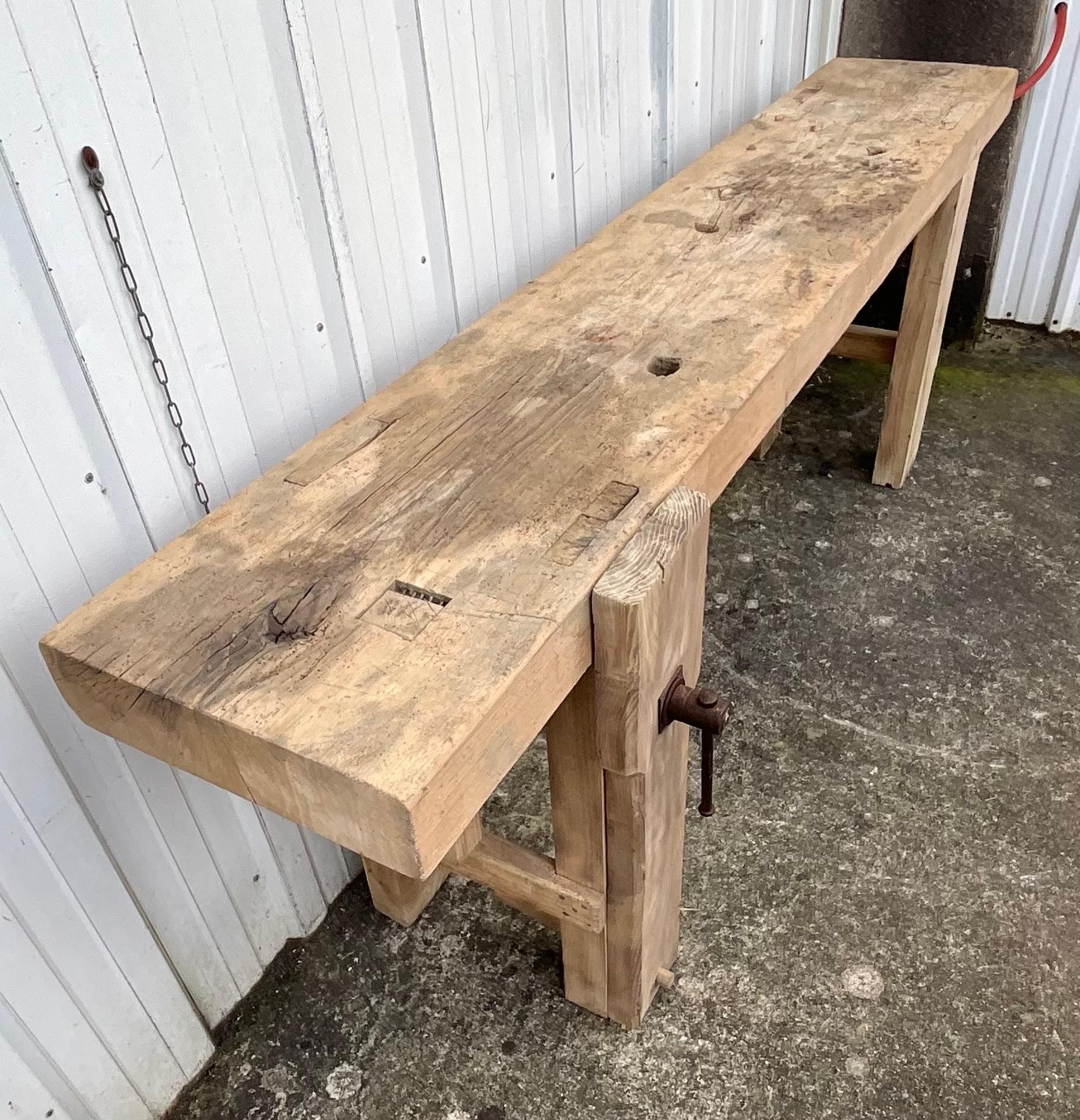 Cet authentique établi de menuisier en hêtre massif date du début du XXe siècle et provient de la vallée de la Loire, en France. Témoignage vivant de l'artisanat traditionnel, il séduit par la force brute de son bois - usé et adouci par le temps -