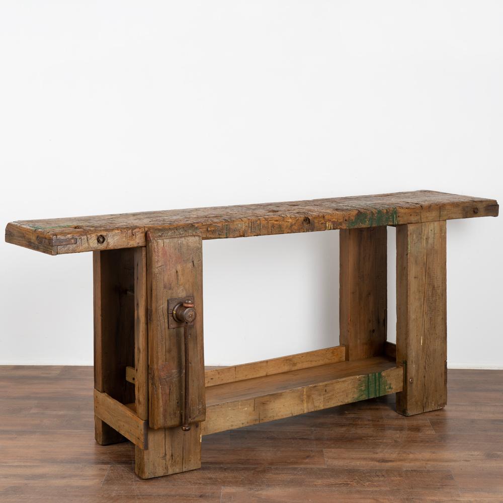 Antique French carpenter's workbench rustic console table with lower shelf.
The years of constant use revealed in every ding, gouge, stain, paint spills (green & yellow) and scratch has enriched the character of this impressive carpenters'