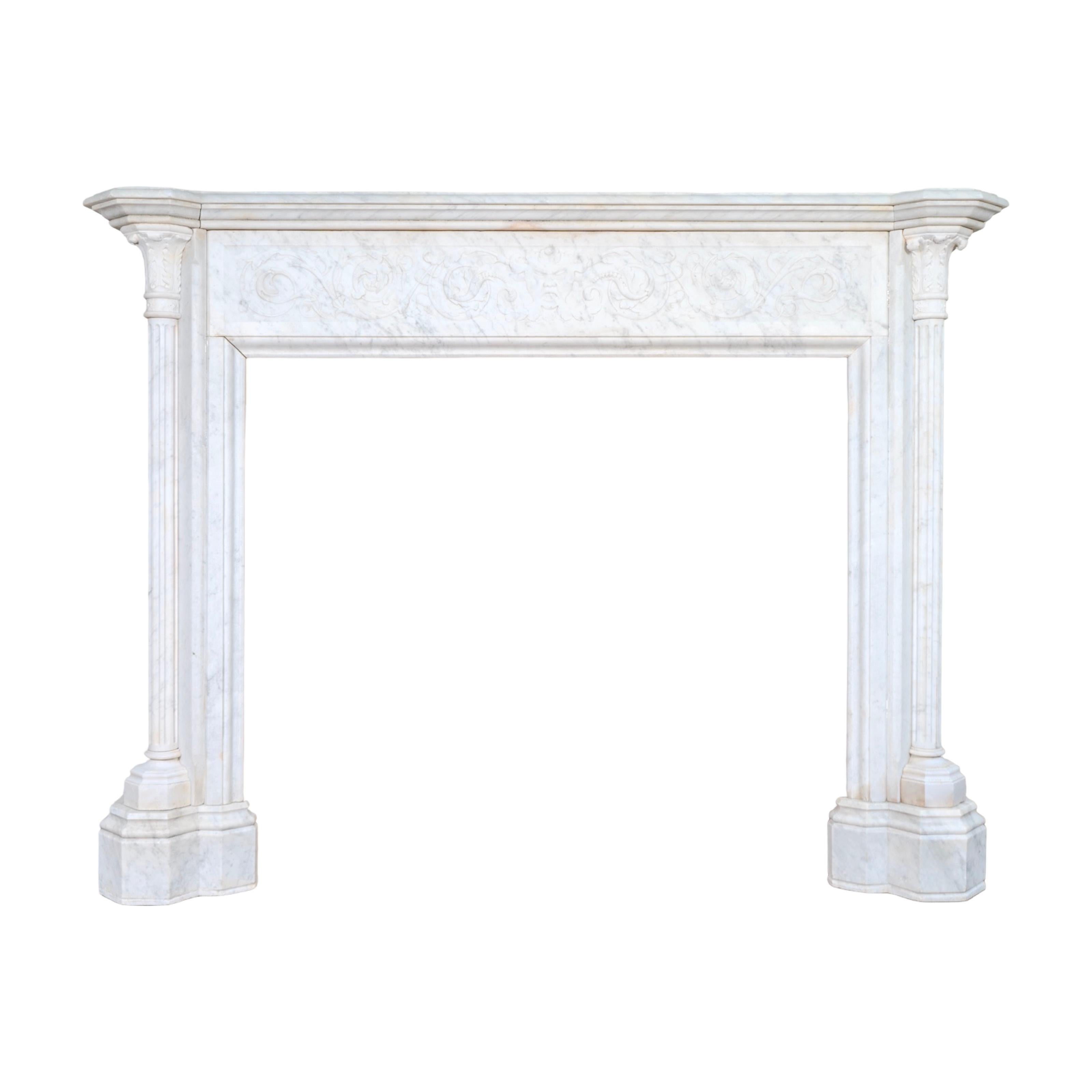 This antique and reclaimed 19th-century French mantel is carved from Carrara marble in the refined Louis XVI style. The frieze is centered with a finely carved mask of Bacchus, the Roman god of wine and festivity, framed by scrolling foliage and