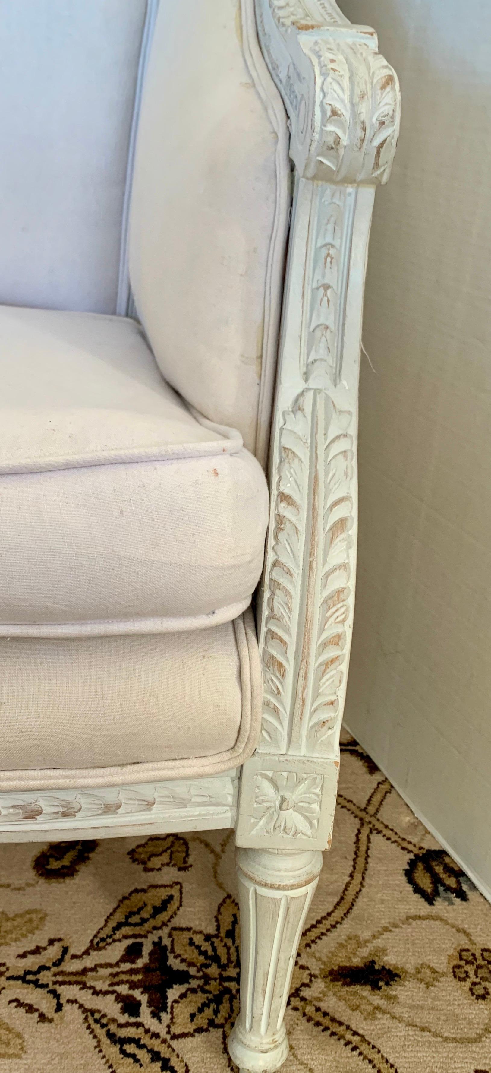 Classic French bergère barrel chairs with beautiful carved details with a white distressed patina.