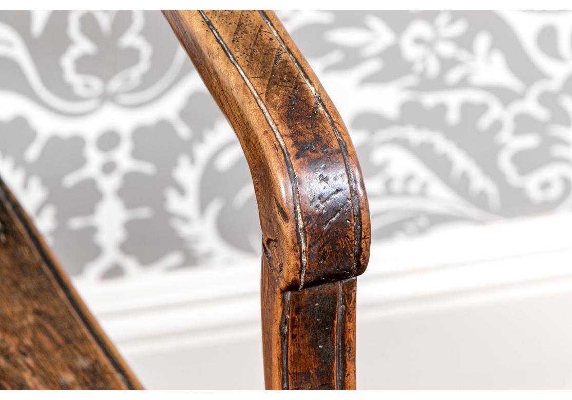 Fauteuil en bois fruitier du 19ème siècle, charmant et usé  avec siège en rotin tiré à la main. La chaise a un dossier en forme d'urne ajourée, des accoudoirs légèrement inclinés, des pieds et des jambes effilés et collés et des accents floraux
