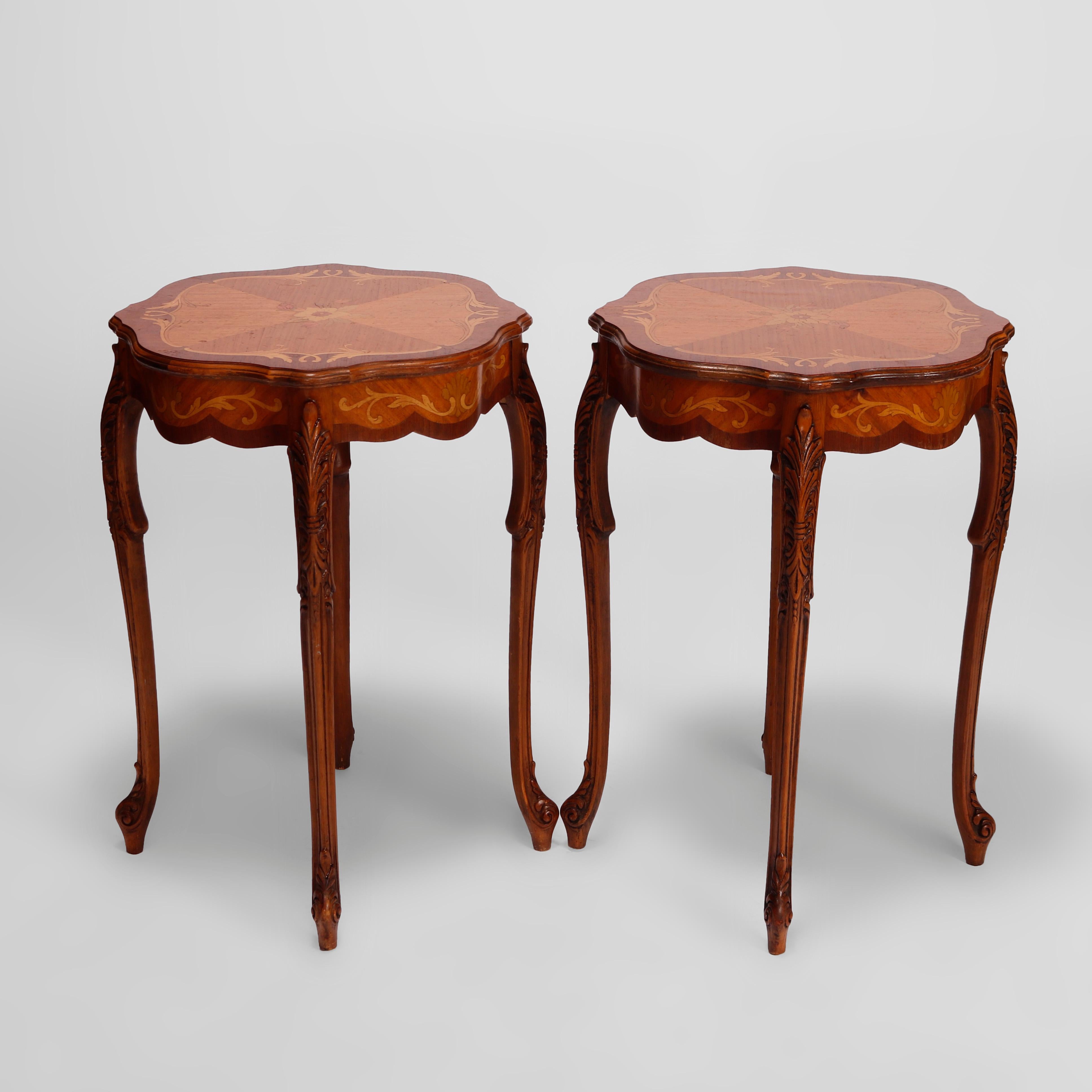 An antique pair of matching French side tables offer mahogany frames with shaped and bookmatched tops having satinwood floral marquetry over shaped skirts and raised on cabriole legs having carved acanthus knees, terminating in stylized scroll feet,