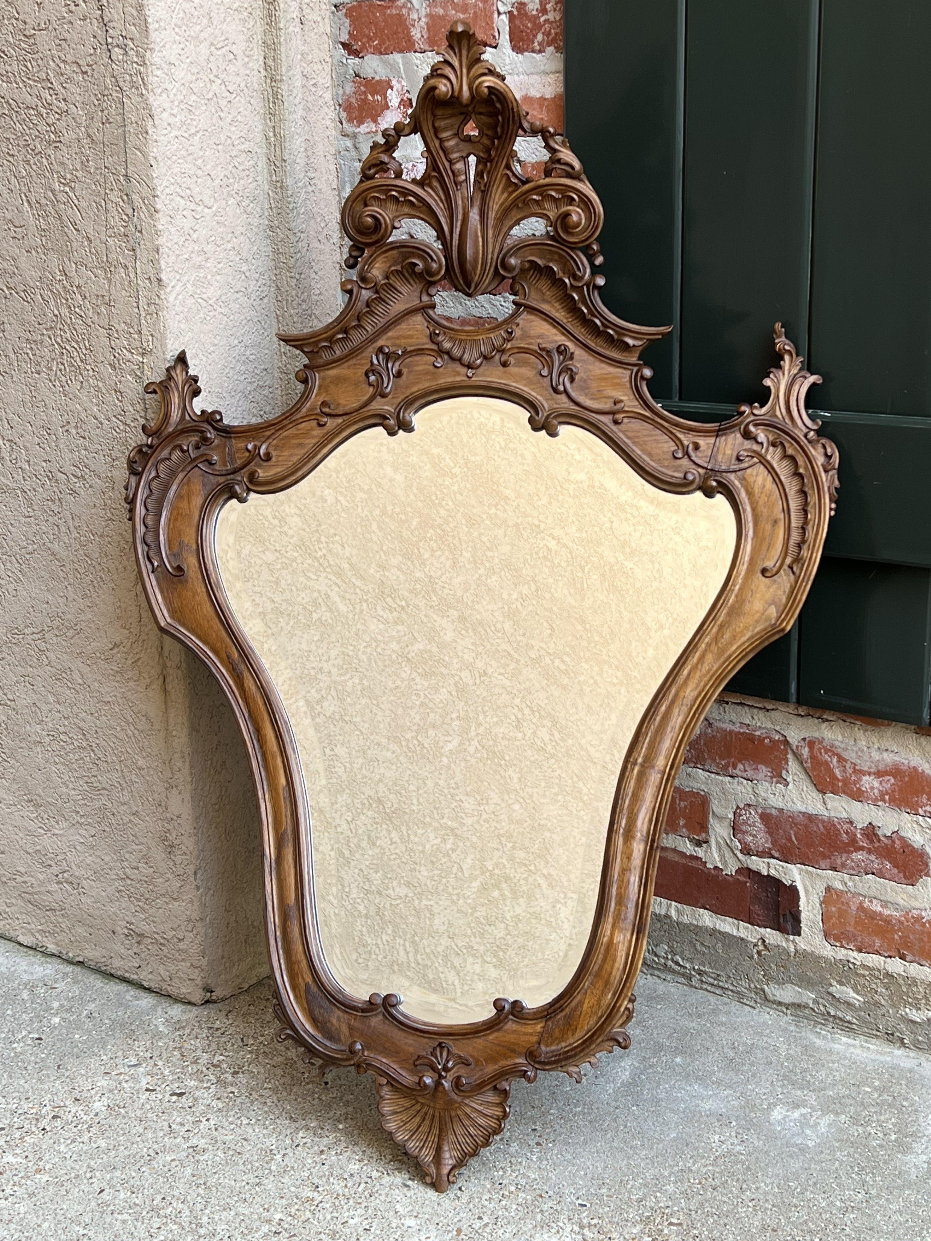 Antique French carved oak beveled wall mirror Louis XV style Serpentine Rococo.

Direct from France, a very ornate wall mirror, with stunning carvings.
Large, shaped crown features an open carved fleur de lis supported by carved serpentine