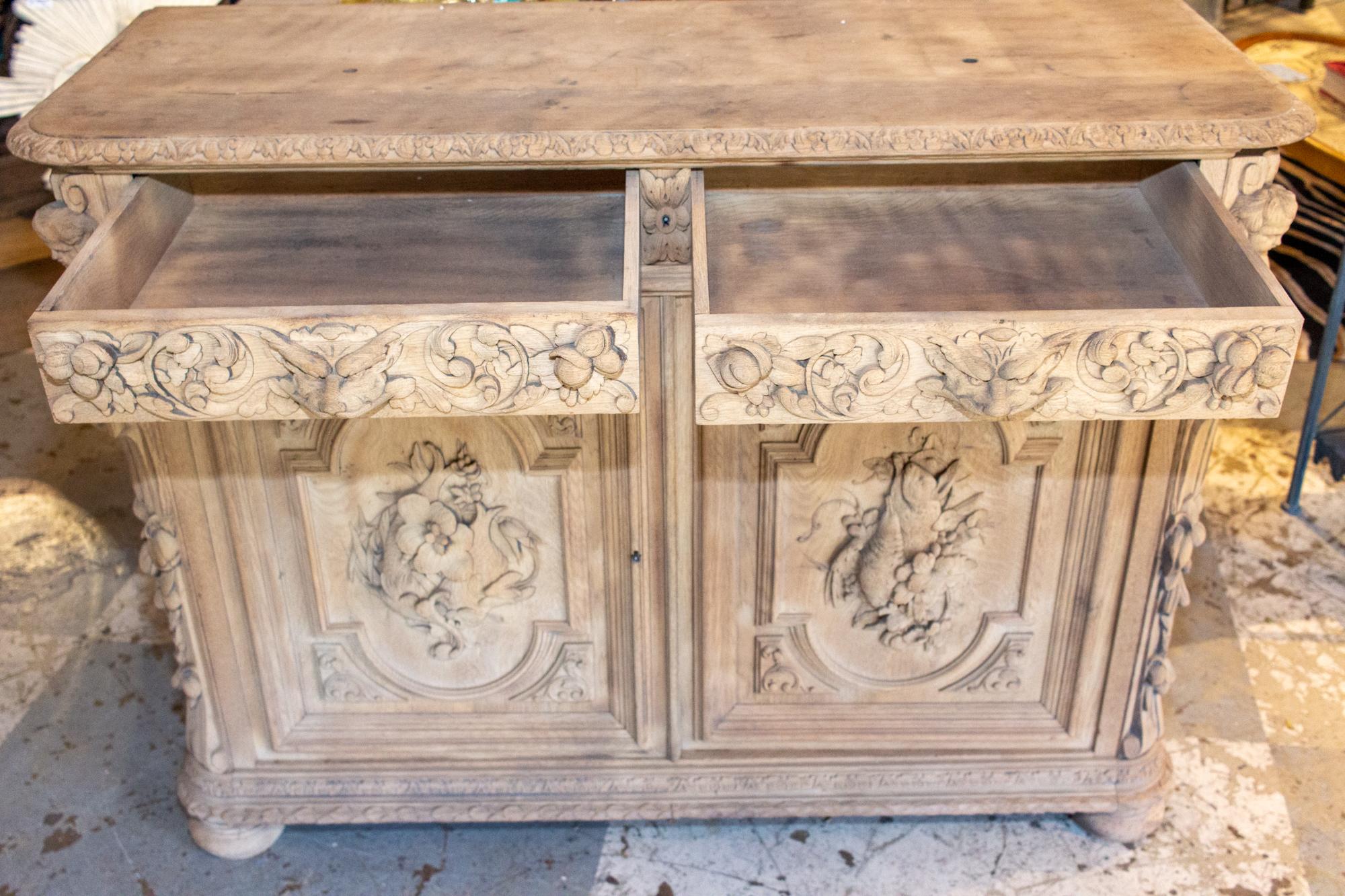This antique French carved oak hunt buffet features carvings on three sides, decorated with images of animals, grotesques and intricate patterns. Two drawers along with ample interior storage allow for plenty of space to stow your items. There are