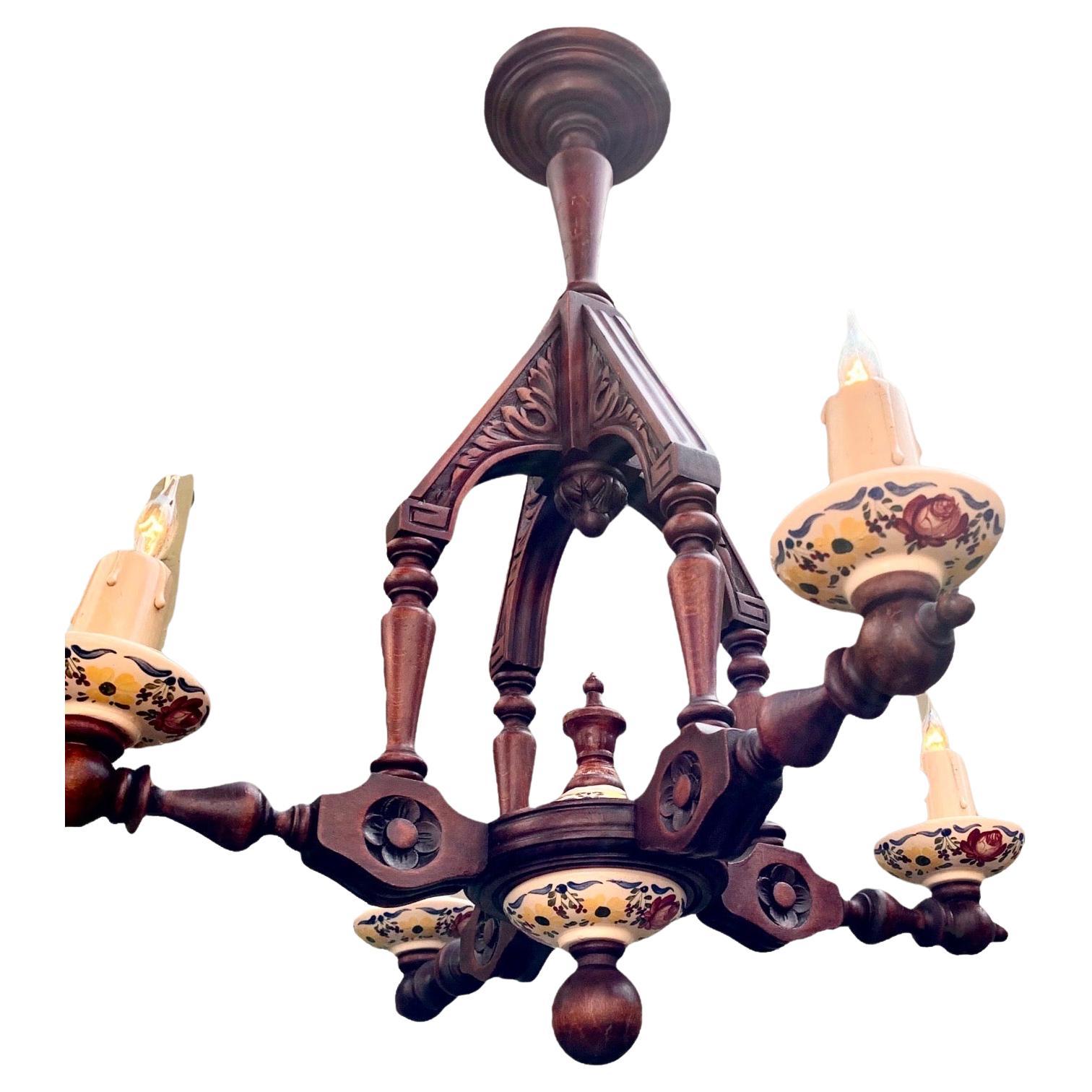 An antique, early 20th century French hand-carved and turned walnut chandelier having delightful and unusual hand-painted faïence bobesch and matching faïence center cups and ball finial. The original and hand-made faïence cups are the show stopper