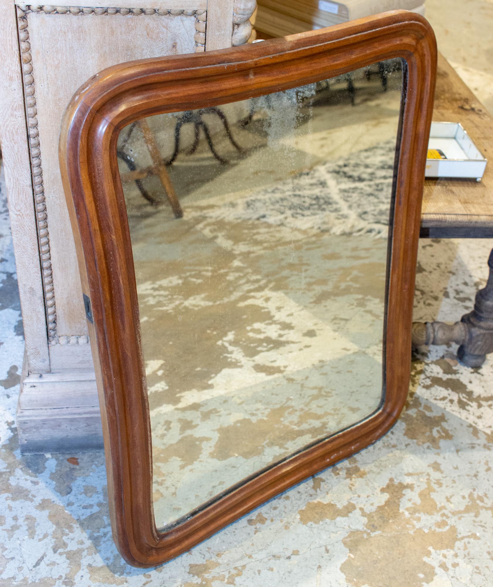 This antique French mirror with original glass has a beautiful carved oak frame with wonderful curves. The outside edges of each side of the mirror have metal hardware that appear to indicate this mirror may have been installed in a piece of