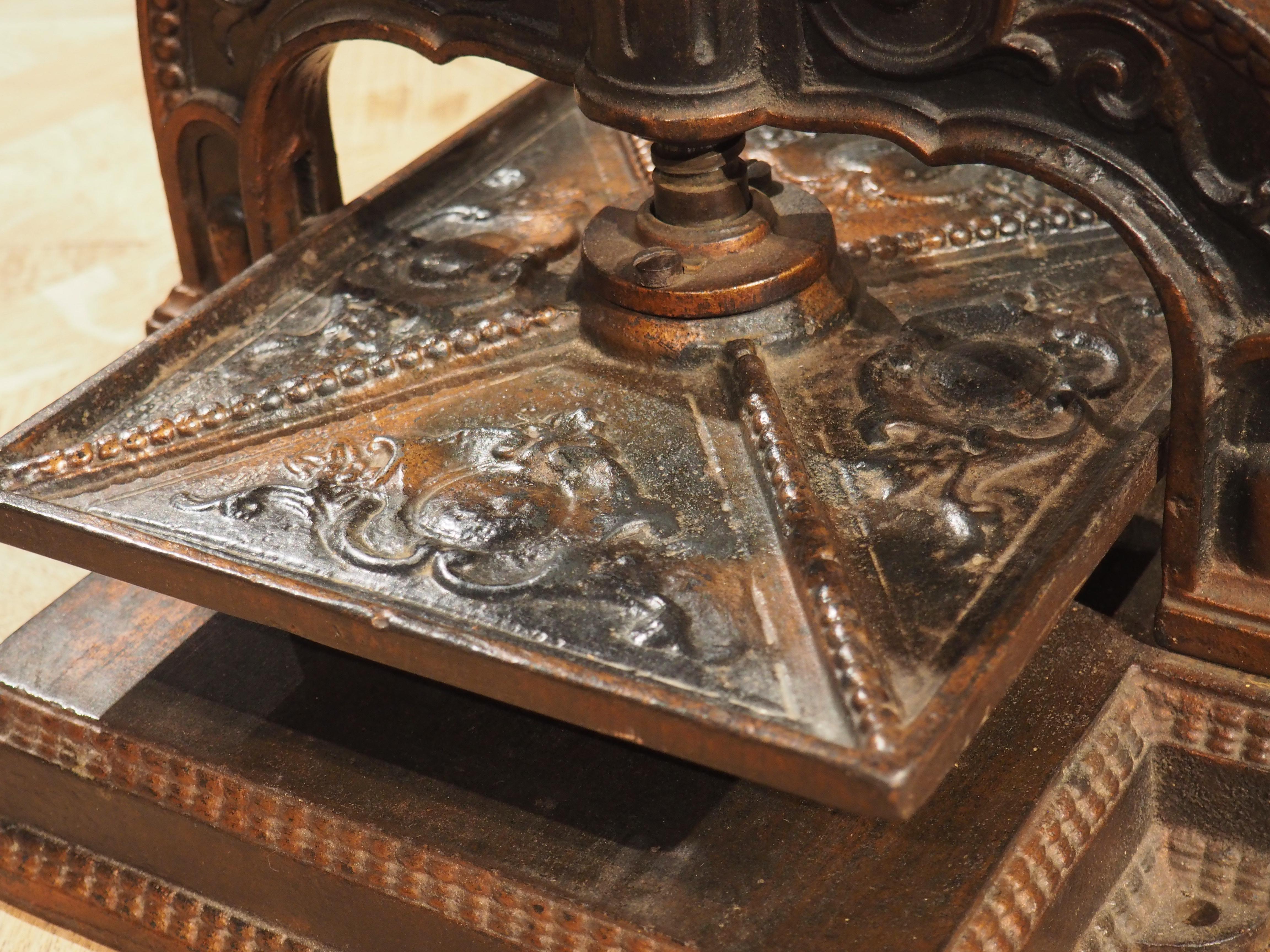 This cast iron piece, known as a book press, was originally used in banks or libraries used to bind documents and books with significant force. This model, from France, dates to the turn of the last century, and it is adorned with interesting