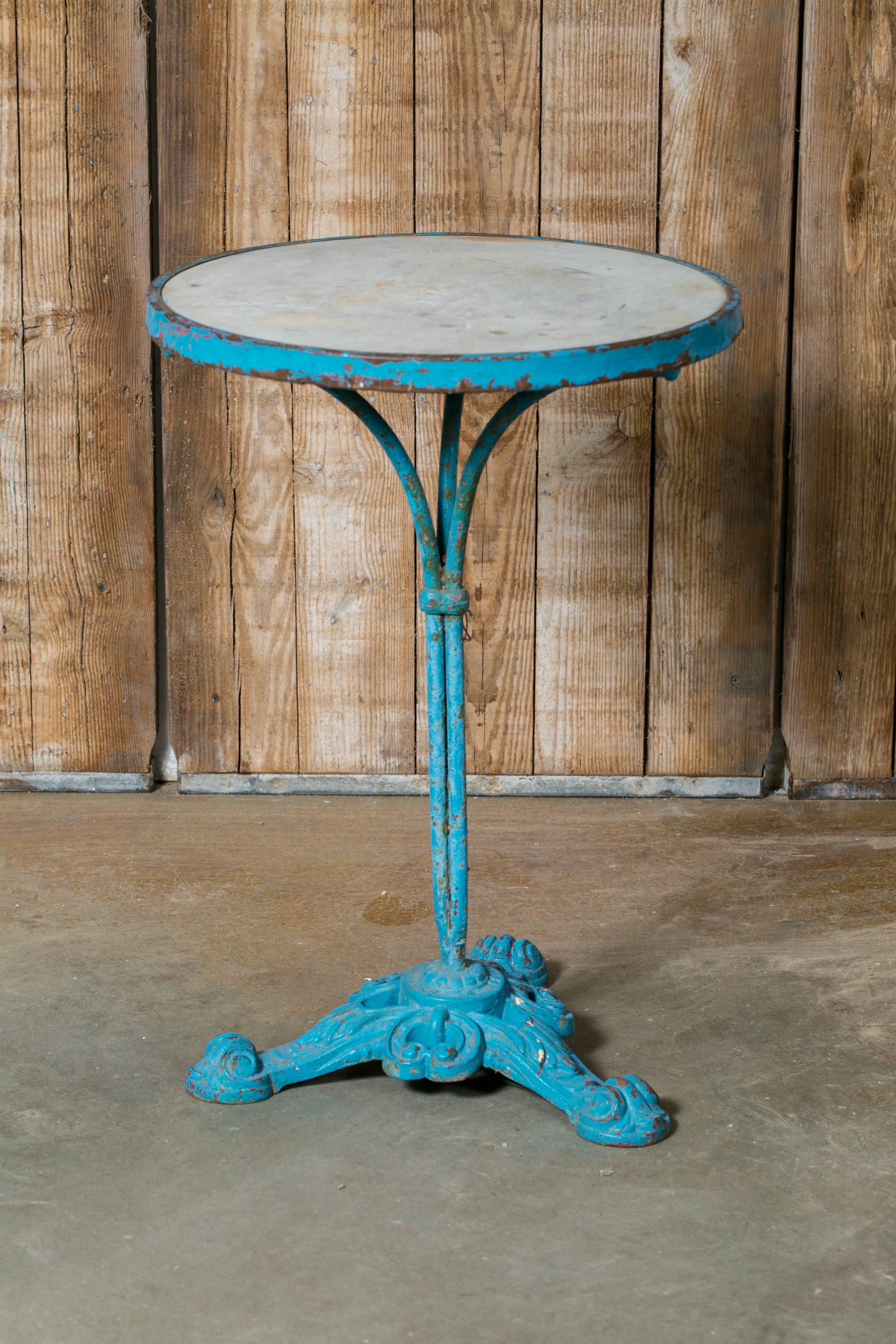 Charming French bistro table with original marble top, brass band and turquoise over-painted iron base. Pretty, decorative three footed base. Would make a great bedside table. From France, circa 1900.