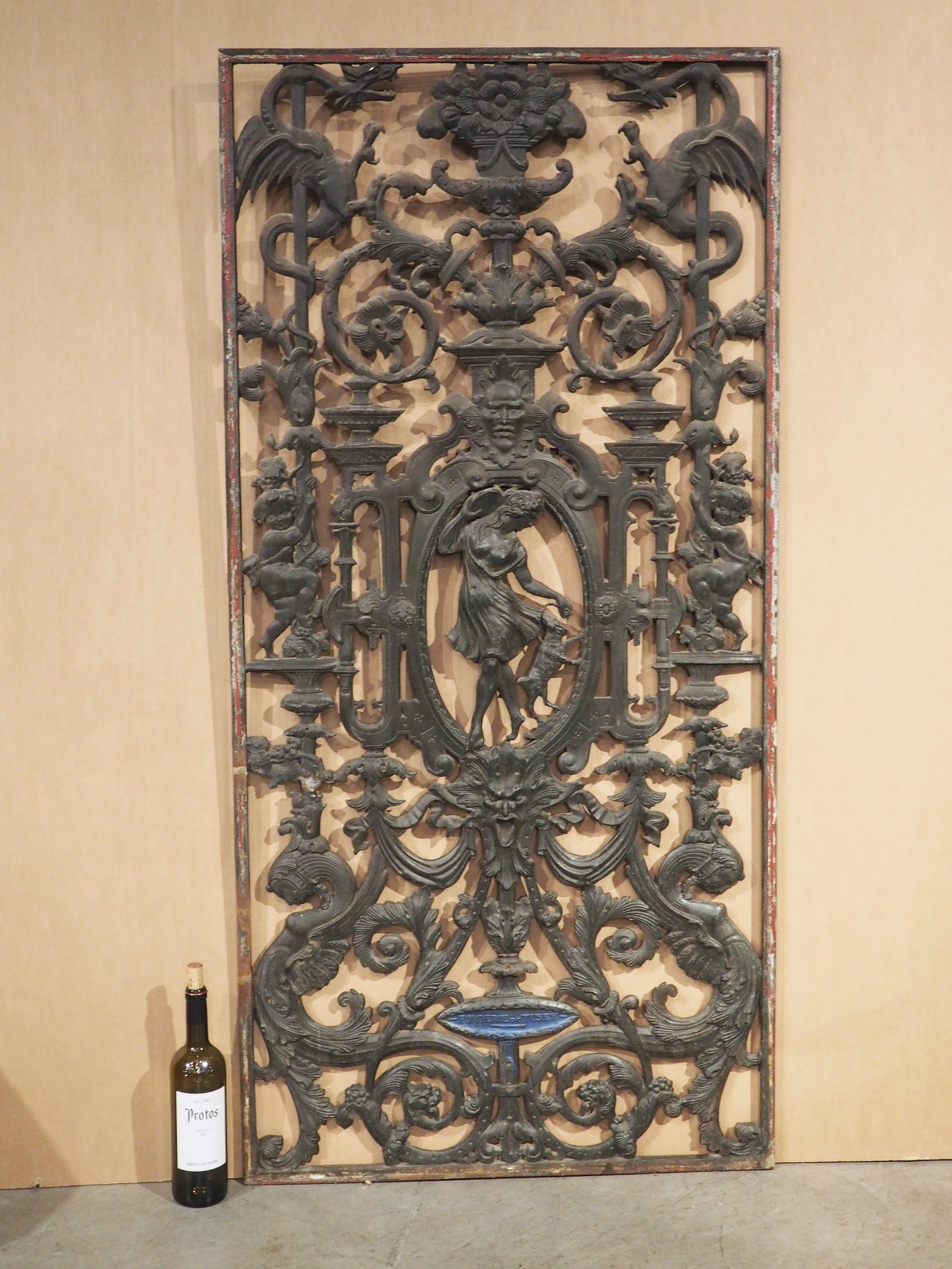 Cast in the 1800s by the well-known French iron foundry, La Fonderie de Tusey, this painted iron gate is comprised of an intricate network of flowers, scrolls, and architecture dotted with mythological figures and mascarons. Detailing can be seen on