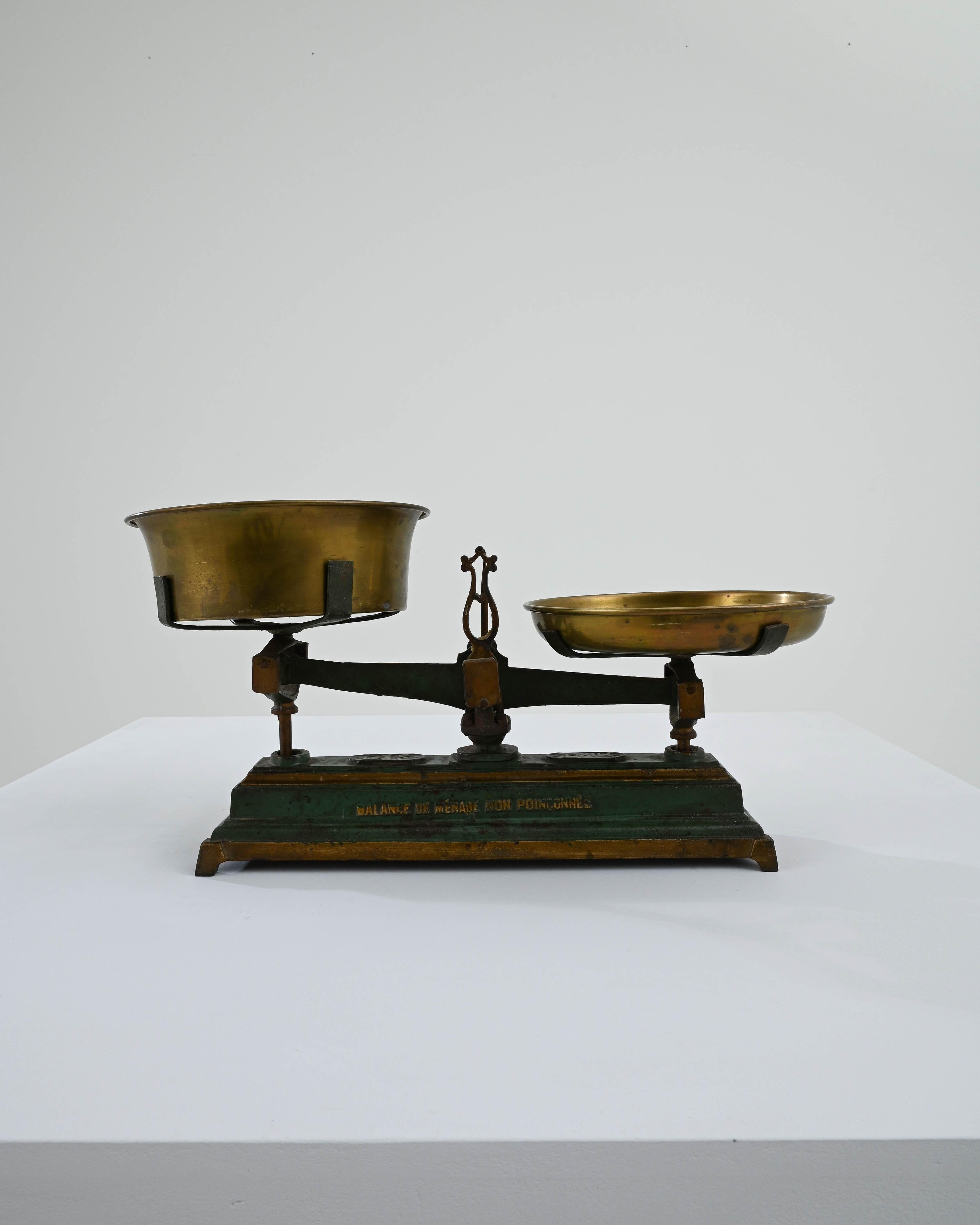 This cast iron scale was made in France, circa 1900. A household and marketplace classic, scales of these dimensions were commonly used to weigh fruits and vegetables. Fully functional, the scale is equipped with brass weighing pans. The trays are