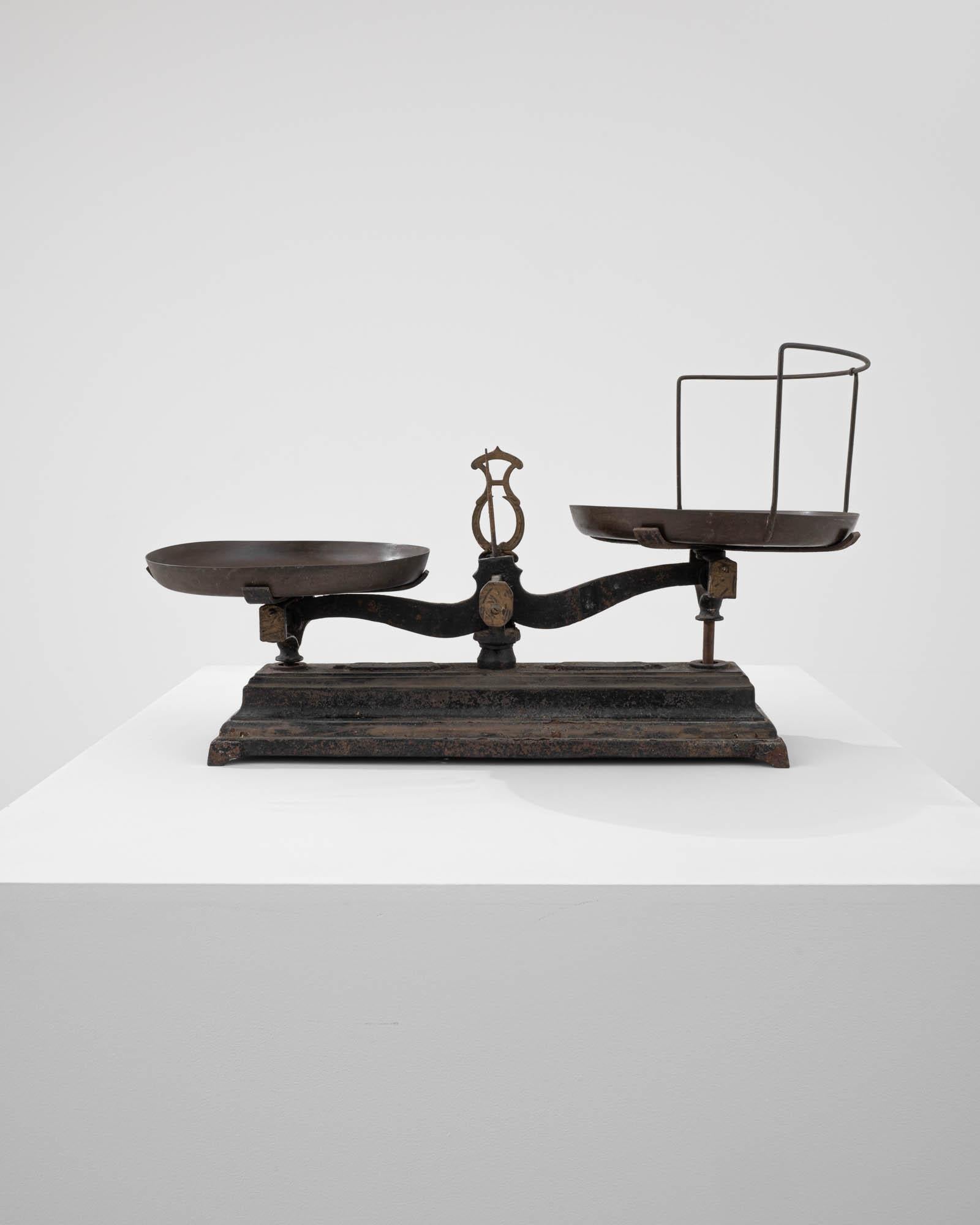 This cast iron scale was made in France, circa 1900. A ubiquitous classic in the home or the market, scales of these dimensions were commonly used to weigh fruits and vegetables. Fully functional, the scale is equipped with brass weighing pans,