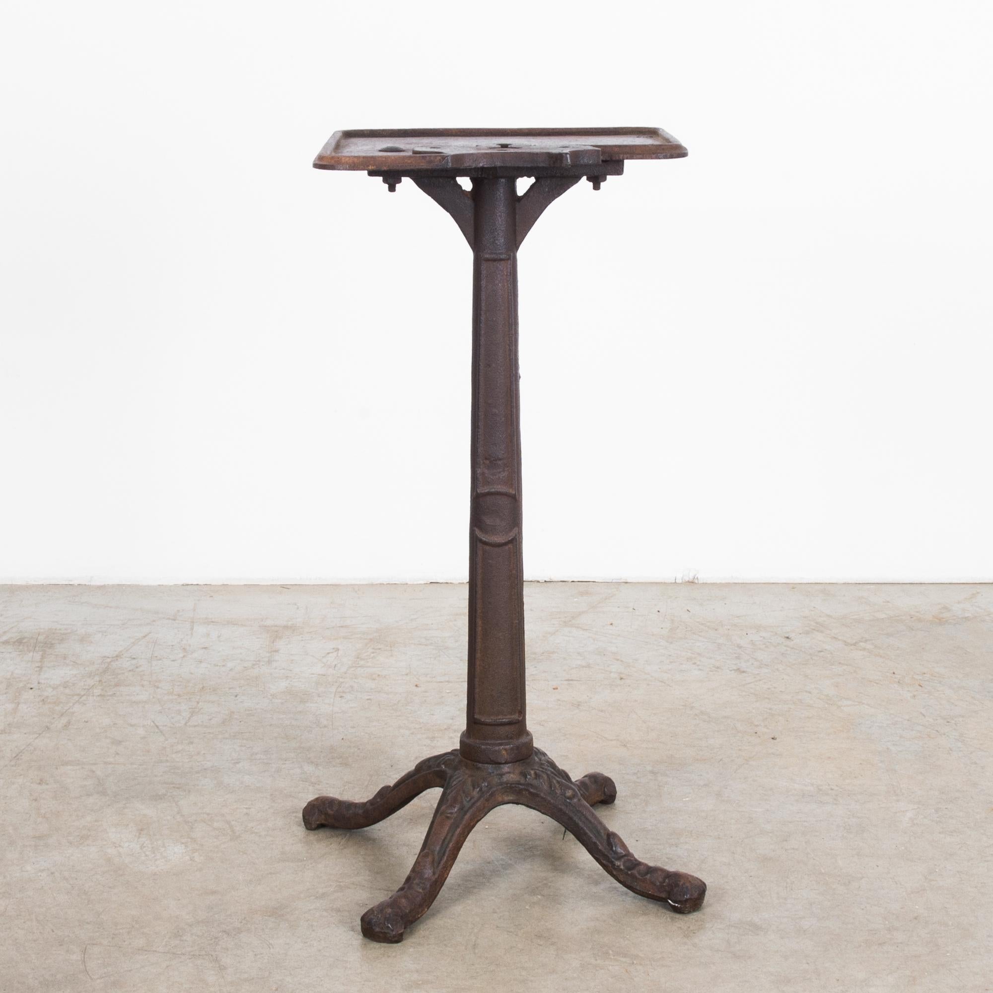 This antique cast iron work table impresses with its timeworn patina. Made in France, timeworn oxidized solidity, is accented with charming details. Floral ornament embellishes the legs of the quadripod stand, while a crown playfully interrupts the