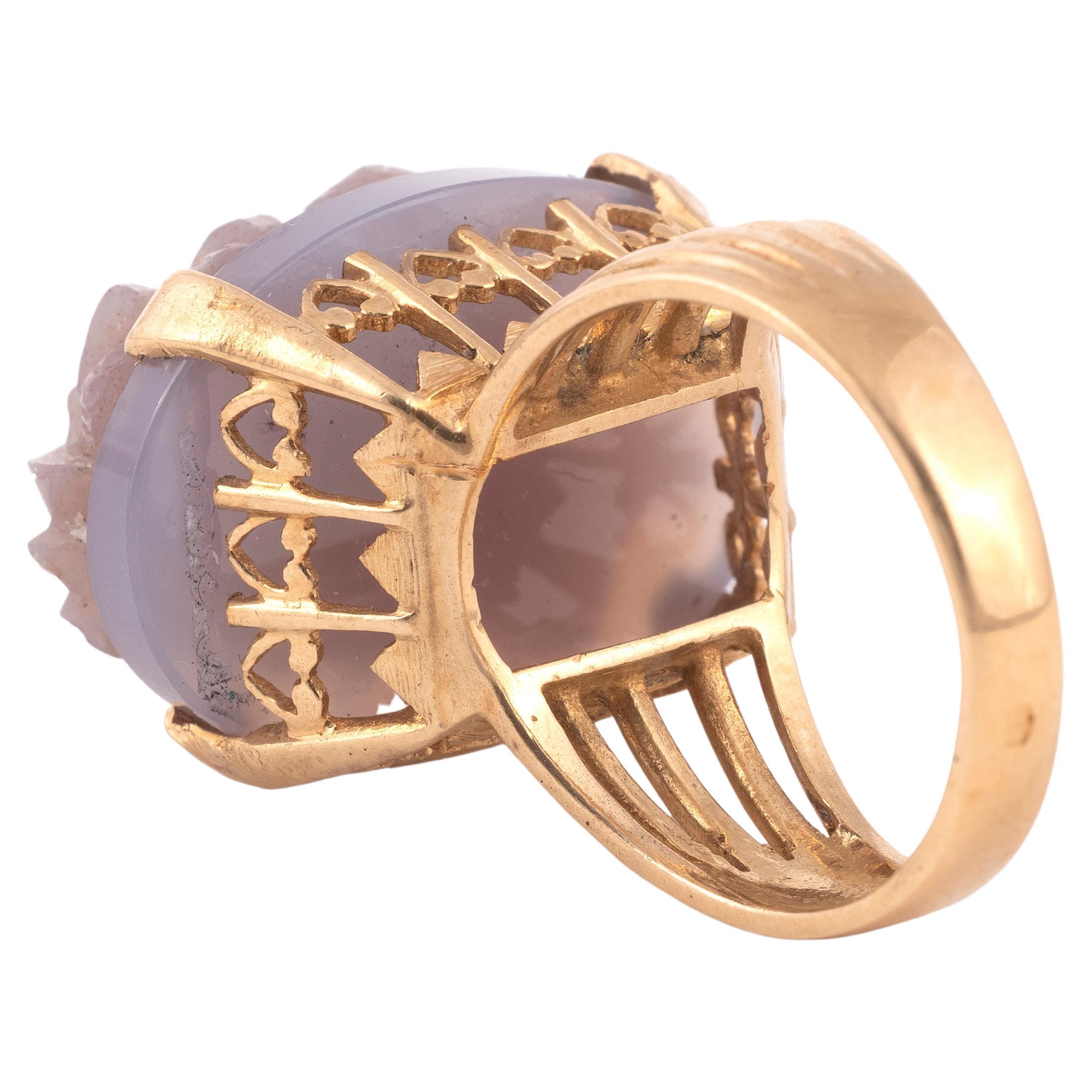 18Kt gold ring set with a cameo on lavender chalcedony stylizing a profile of a man with a waving beard, the setting on five wires and openwork hearts. Top size is 23mm x 21mm
Finger size: 8
Weight: 12 g