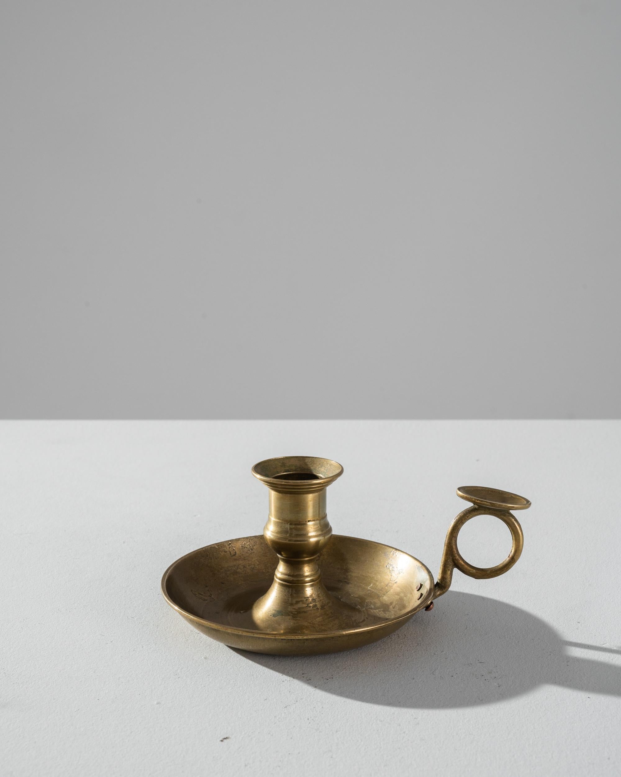 This chamberstick candle holder was made in France circa 1900. That tiny flame, preserved in wax, an ancient tradition of necessity and pleasure: providing light, emitting heat, pleasant fragrances, and keeping time. This elegant brass holder was