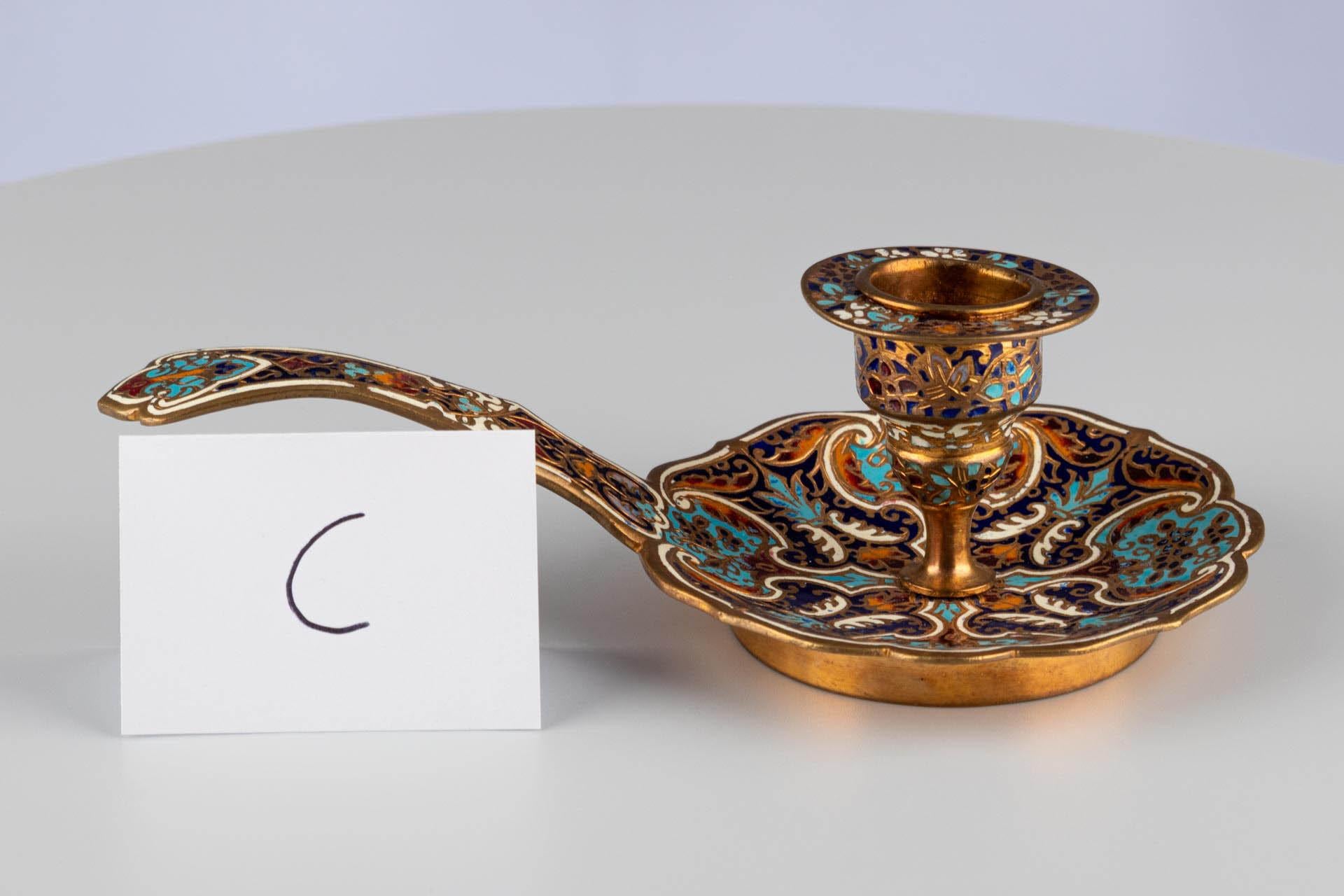 Antique French Champlevé Emaille Messing Gold Blau Kammer Kerzenleuchter 

Französisch
Messing, Emaille
c. 1900 

Abmessungen: H x B x T: 6 cm x 16 cm x 9 cm

Dieser detailreiche Kammerleuchter, der um 1900 hergestellt wurde, zeigt eine komplexe und