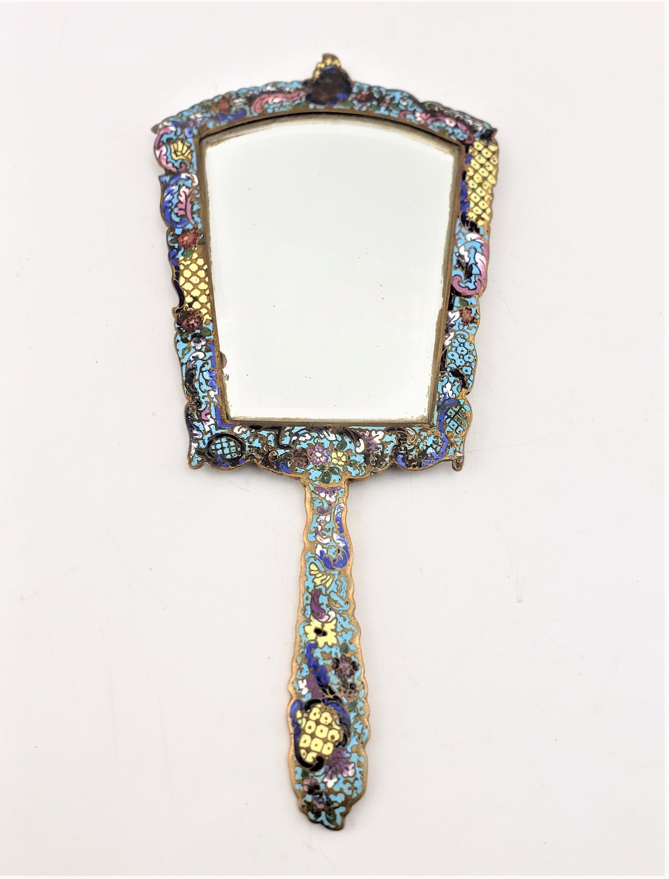 This antique dresser mirror is signed with initials by an unidentified maker, but presumed to originate from France and dating to approximately 1900 and done in the period Art Nouveau style. The shield shaped hand mirror is done in brass with nicely