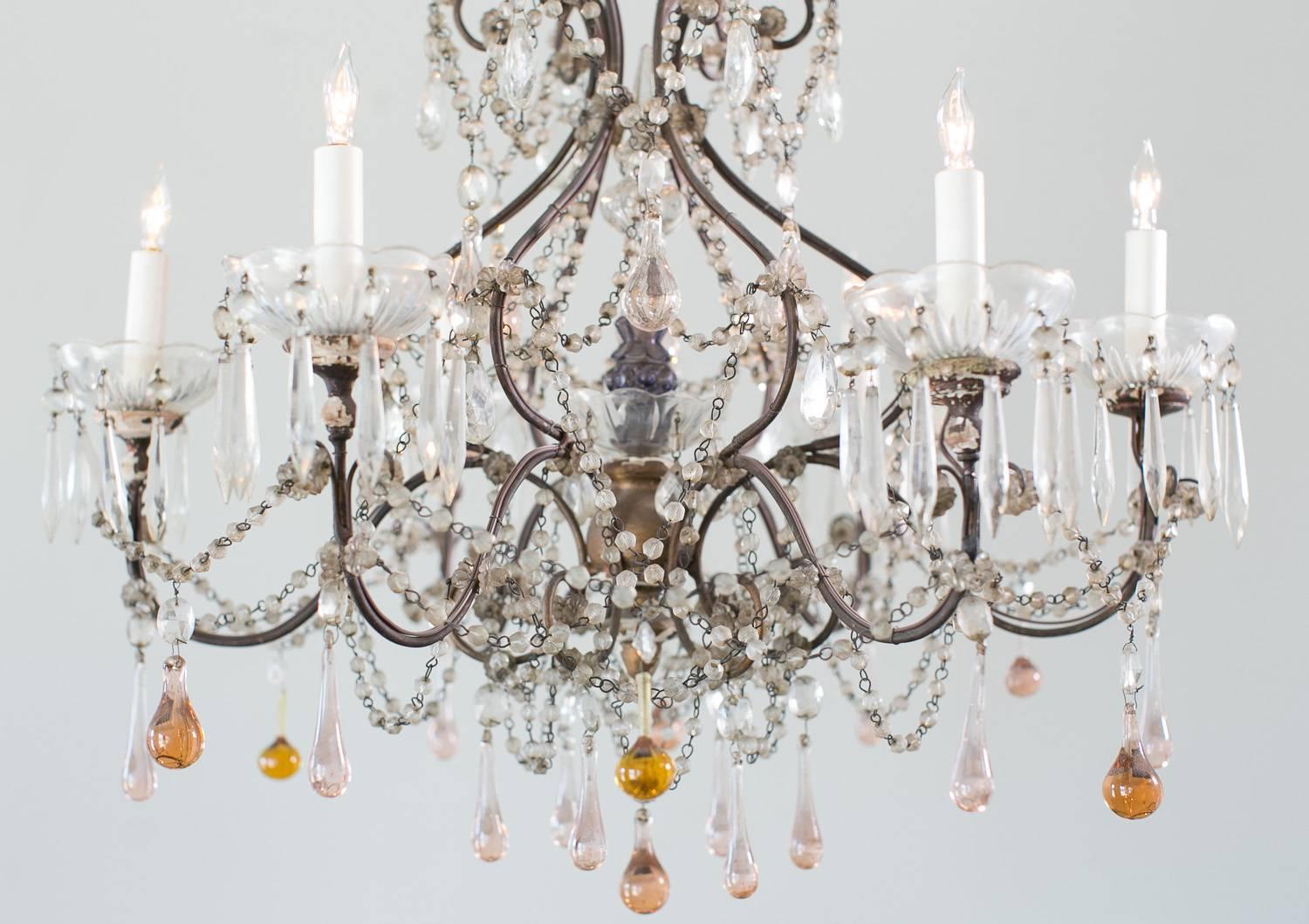 Delicate antique chandelier with a plethora of small crystal beads interconnecting the six arms. Light, peach colored teardrop crystal balls decorate the underside of this fabulous light. The center features a lovely mix of beads and faceted