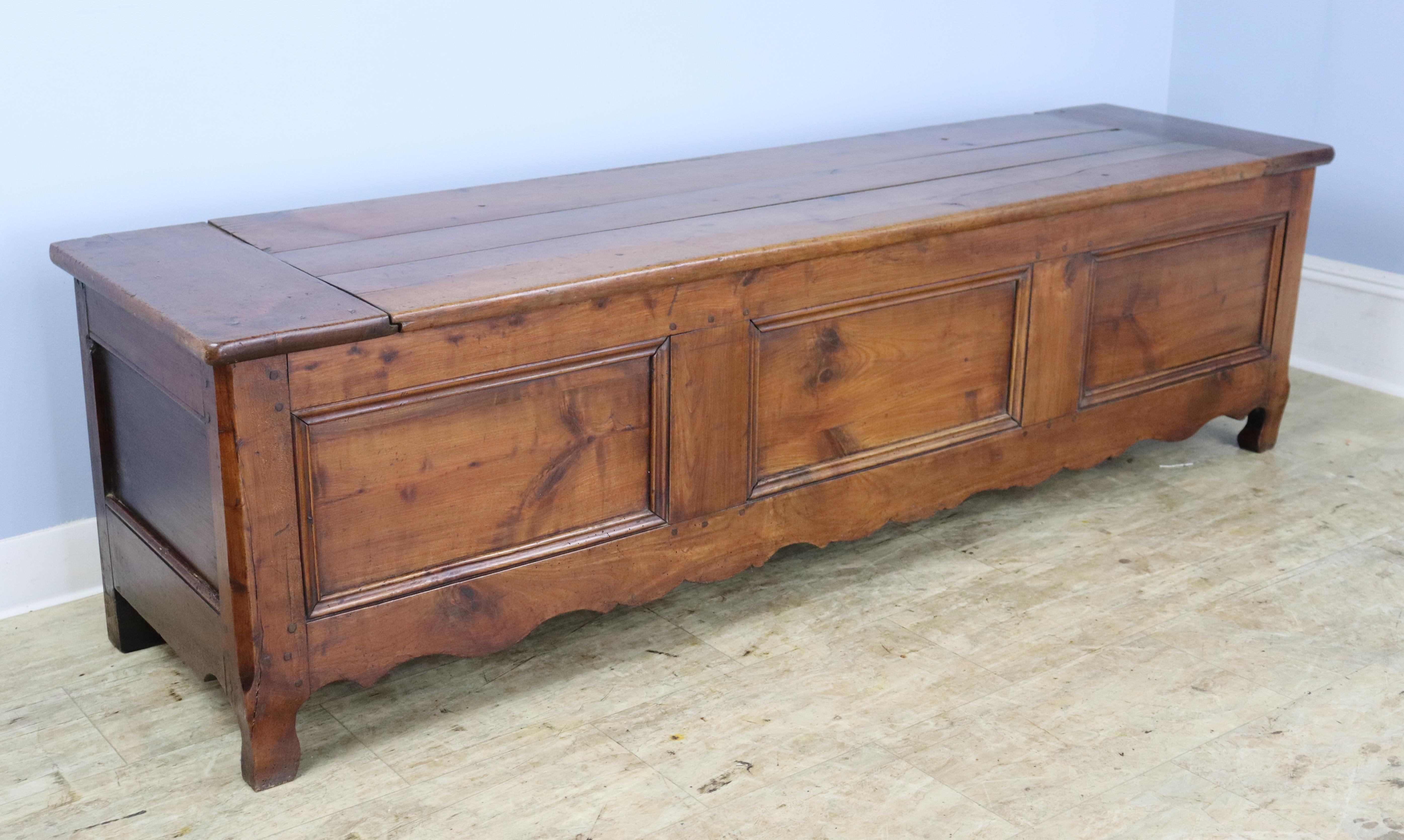 A pretty cherry coffer or bench with a removable (non-attached) top and plenty of storage within. Charming carved apron and good color and patina. This piece would be right in the end of a bed in the entrance hall or well-appointed mudroom.