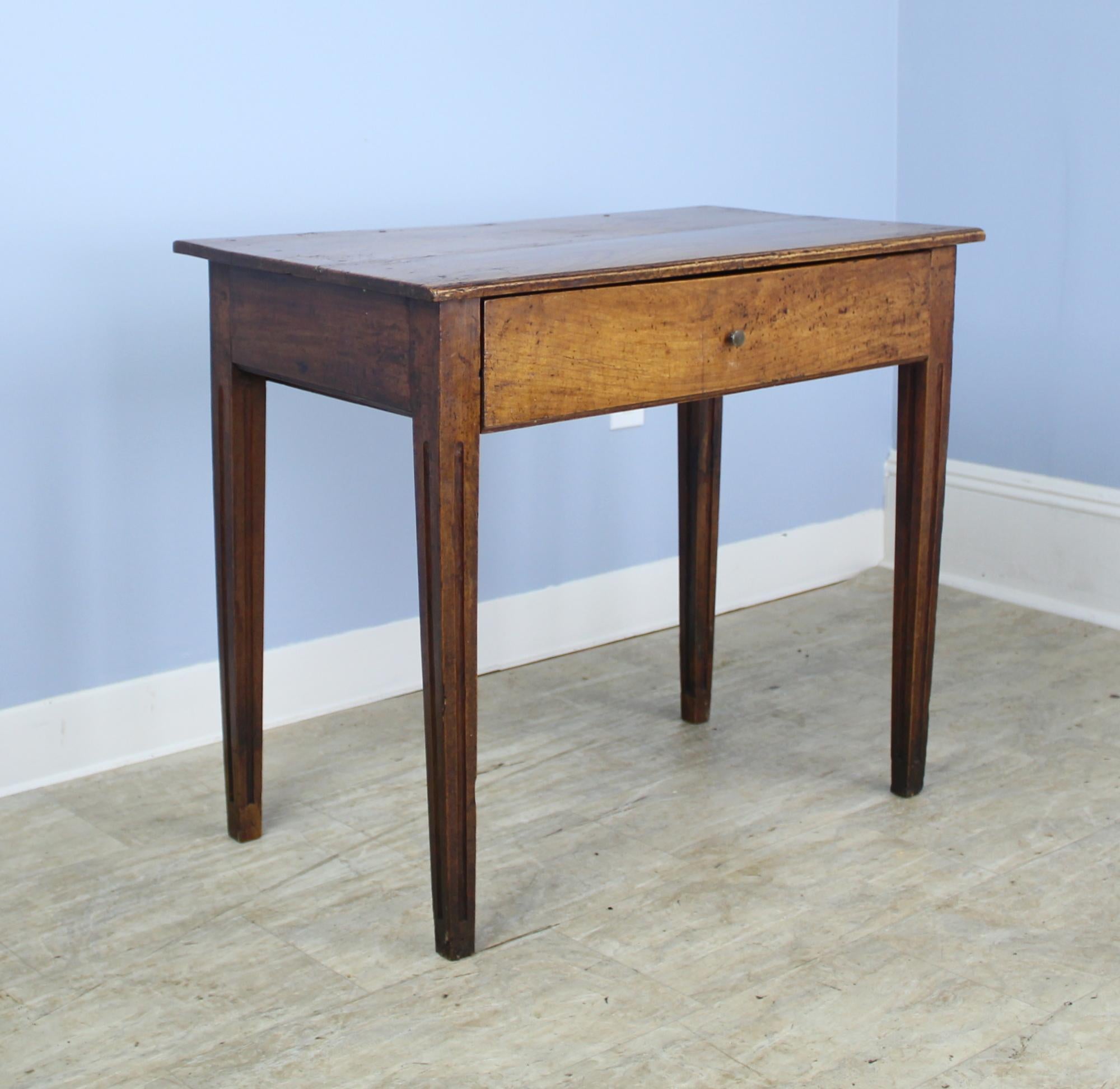 A sweet French side table in warm cherry with a single deep drawer, stylized legs and a reeded edge on the top. This table has very good color and patina, with some interesting old distress.