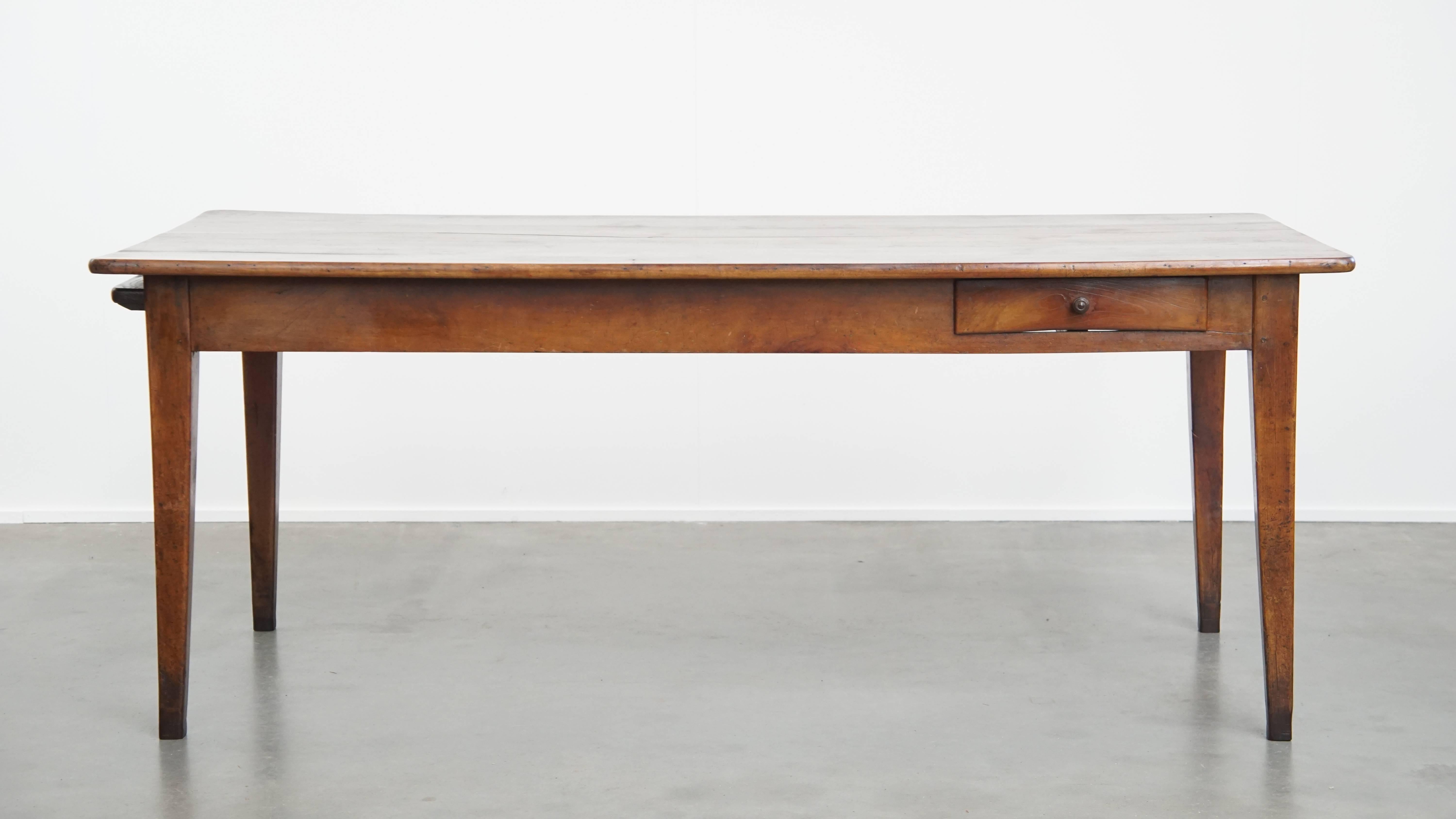 Cette table de salle à manger française ancienne est fabriquée en bois de cerisier dans un beau ton chaud, avec un grand plateau extensible et un tiroir pratique. Cette superbe table, datant du XIXe siècle, est une pièce polyvalente qui s'intègre