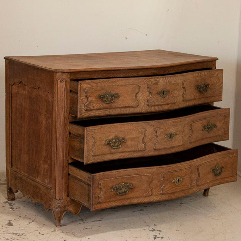 Lovely carved paneling accent the serpentine drawers and sides of this attractive oak chest of drawers. Notice the scalloped edge along the bottom and cabrioet feet, additional details of the fine French styling of this handsome chest of drawers.