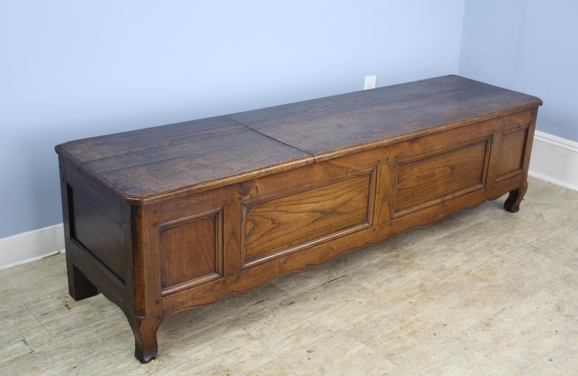 A pretty chestnut coffer or bench with a hinged top and plenty of storage within. Charming carved apron and good color and patina. This piece would be right in the end of a bed in the entrance hall or well-appointed mudroom.