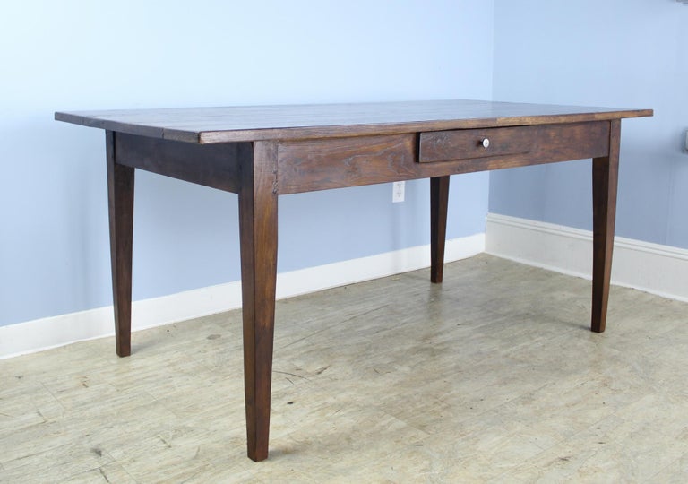 A handsome smaller French dining or farm table with rich color and nice patina. This table has a single roomy drawer. Apron height of 24.75 inches is very good for knees and there are 53.5 inches between the legs on the long side.