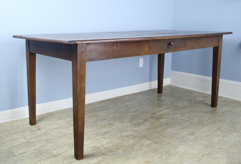 A handsome and generously proportioned French dining or farm table with rich color and nice patina. This table has a breadboard at one end and a single roomy drawer. Apron height of 25.75 inches is very good for knees and there are 66.5 inches