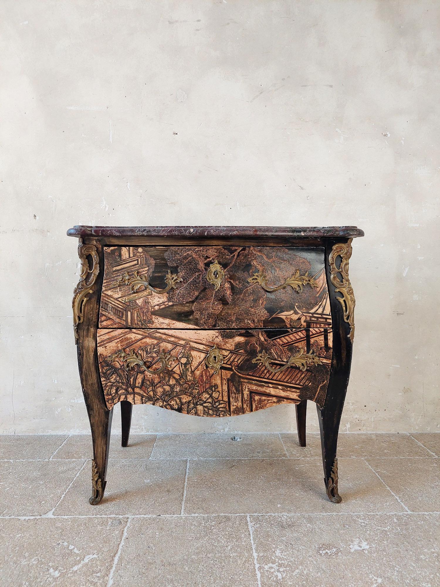 Antique French chinoiserie commode. 19th century black painted chest of drawers with carved details in shades of beige, red and green. With beautifully shaped brass details on the corners and the front feet, the closures and handles. The red marble