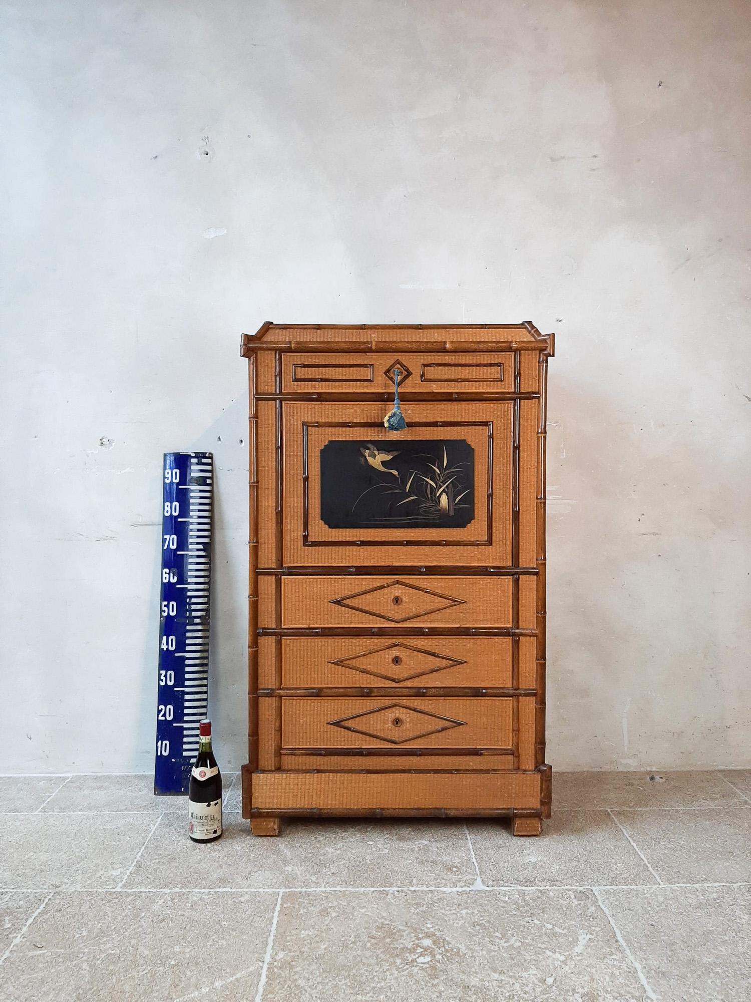 Antique Chinoiserie française secretaire à abbant.

Ce meuble est fini avec des garnitures en bambou autour de panneaux noirs laqués en rotin avec des oiseaux.

A l'intérieur du rabat s'ouvrent de beaux tiroirs en tissu bleu et laqué noir.