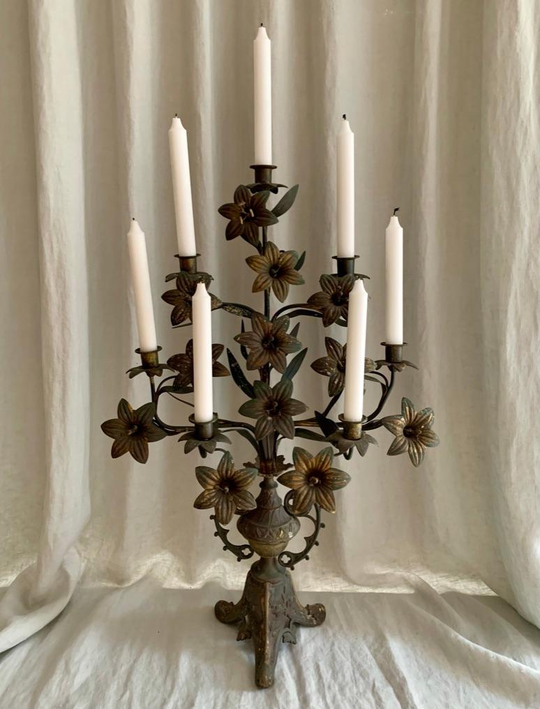 Antique French patinated brass church candelabra decorated with lilies and leafs. The candelabra has a beautiful darkened patina and can hold seven candles. These antique French candelabras used to adorn the catholic churches throughout France and