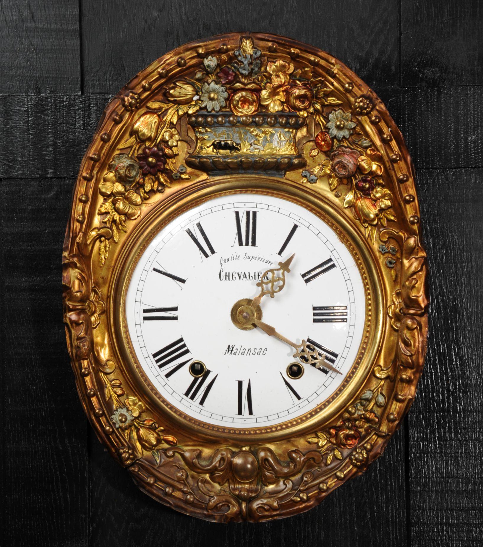 A charming antique French comptoise clock dial, beautifully naïve repoussé work surround with painted decoration, porcelain enamel dial with brass hands. Originally with a large weight driven movement, this was substantially missing. Our clockmaker