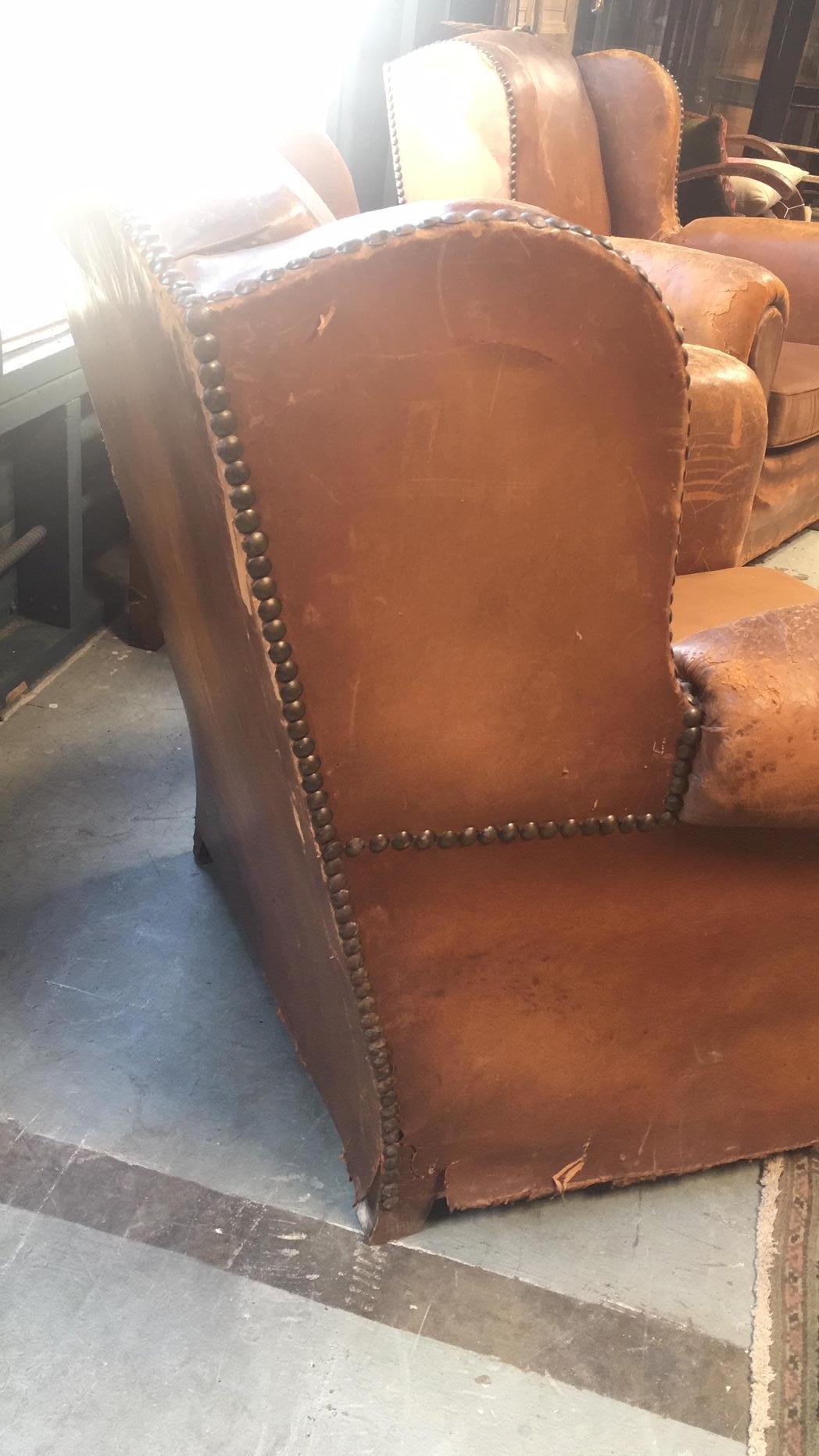 Antique pair of club chairs from the 1920s. Leather with studs. Seat cushion is not leather but rather fabric.