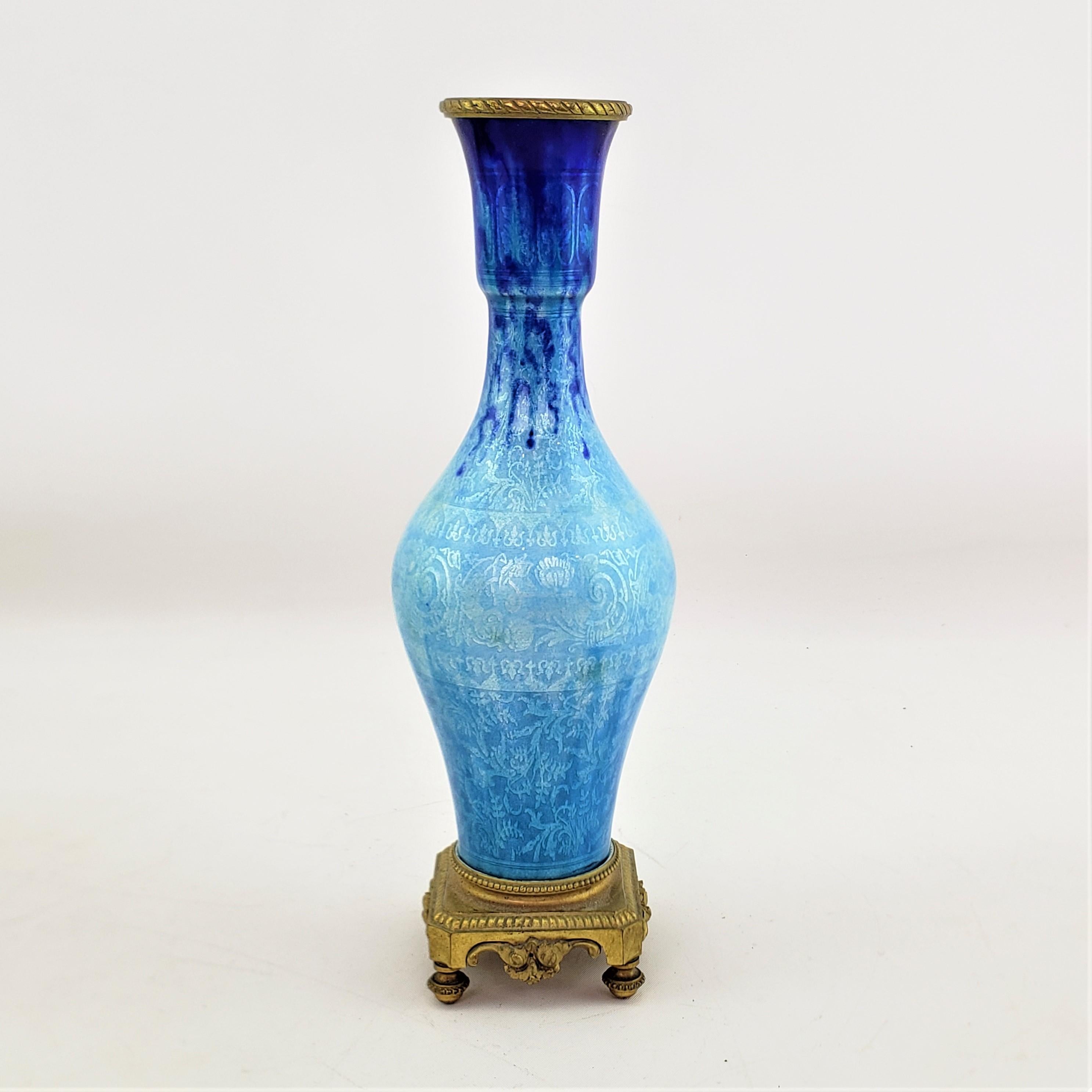 This antique vase is unsigned, but presumed to have originated from France and date to approximately 1920 and done in a period style. The vase is composed of brass with a vibrant cobalt blue enamelling from the top, turning to a silver turquoise in