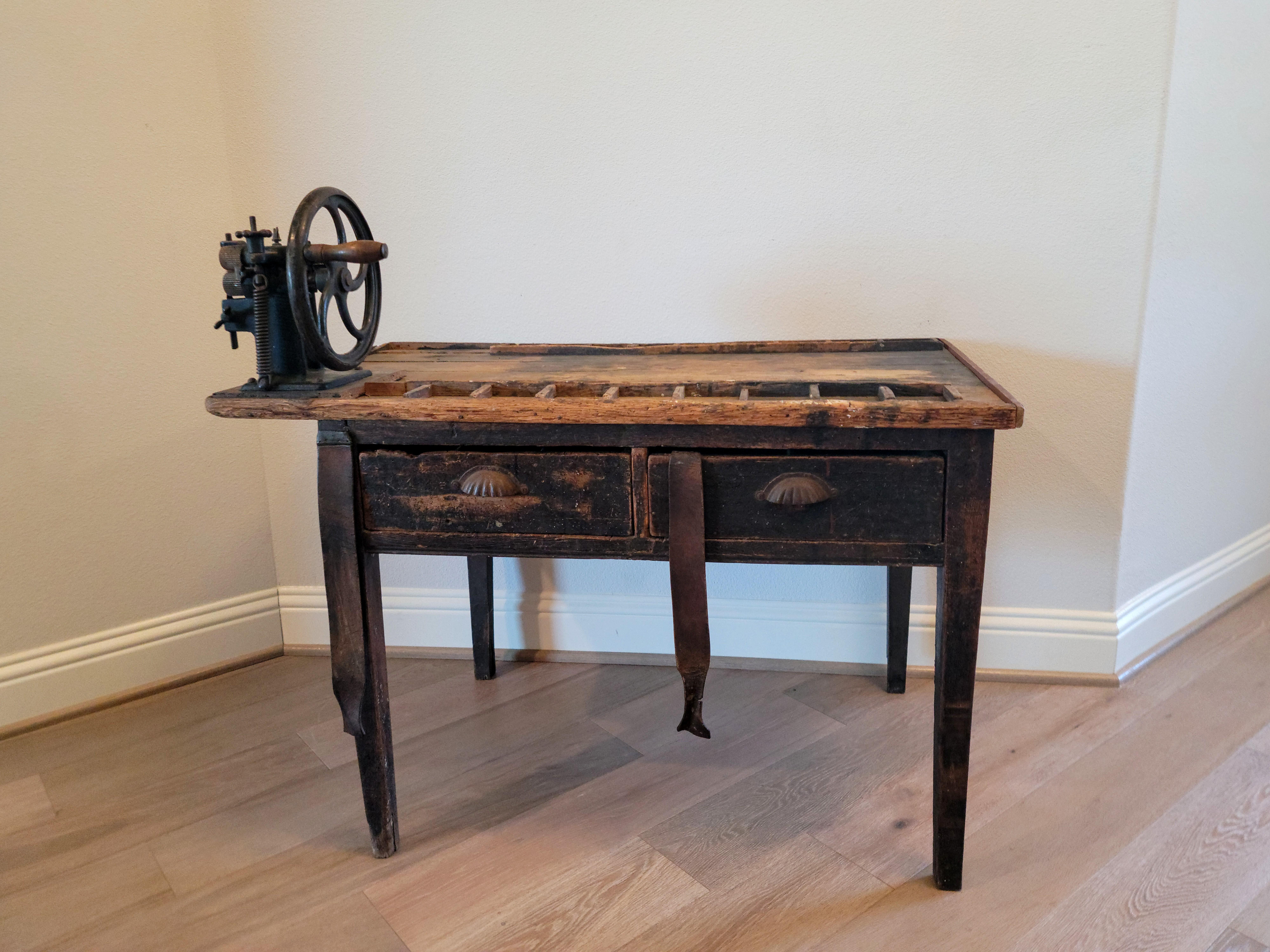 A scarce French cobblers / leatherwork shop workbench with beautifully worn distressed patina!

Dating to the turn of the late 19th / early 20th century, featuring a rectangular plank boarded top, slightly overhung on the left and mounted with a