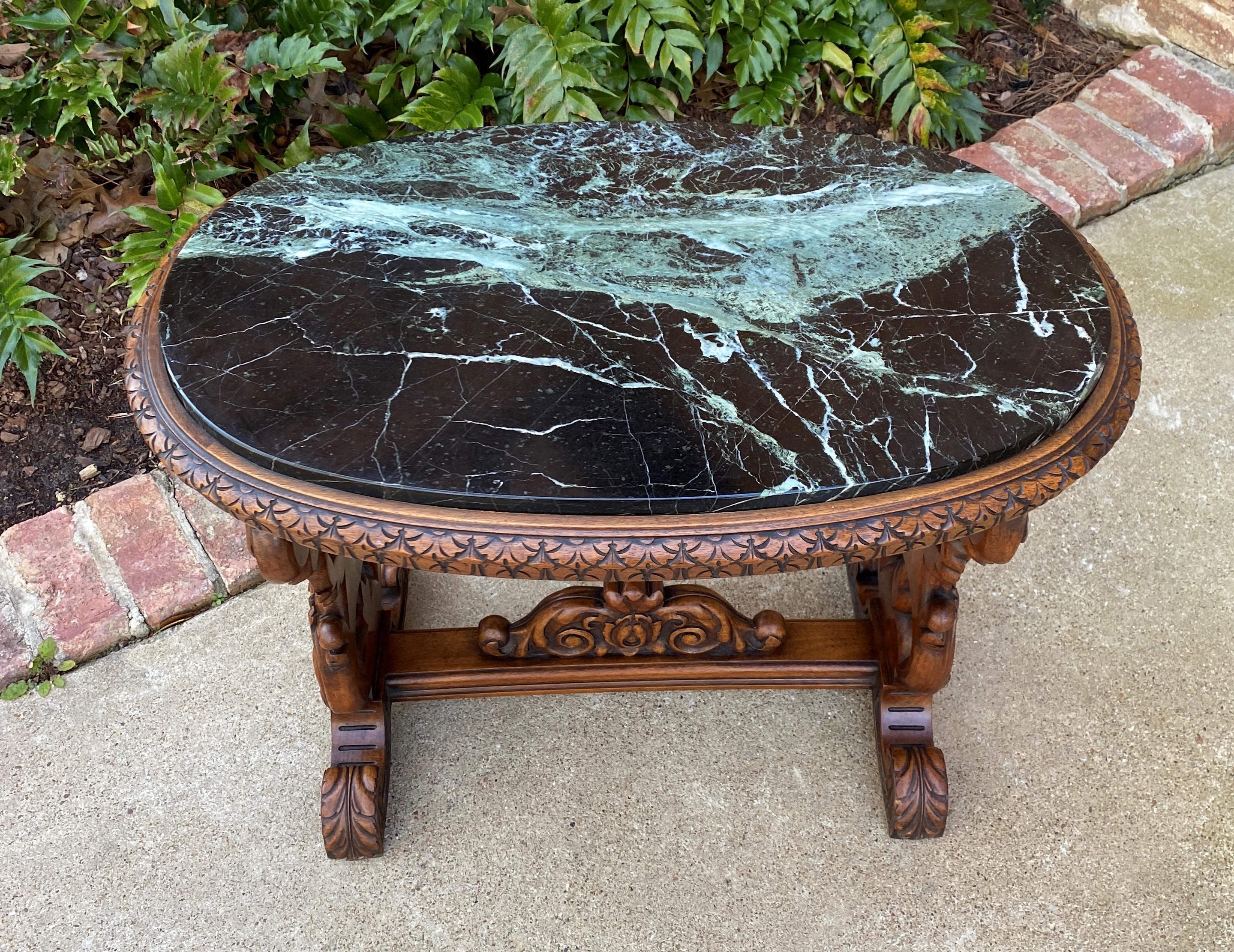 Unique antique carved French Renaissance Revival oval coffee table or bench with green marble top in walnut~~c. 1920s

 Nicely carved cherubs and rosettes on sides and stretcher~~green marble top with beautiful veining

Versatile piece with so