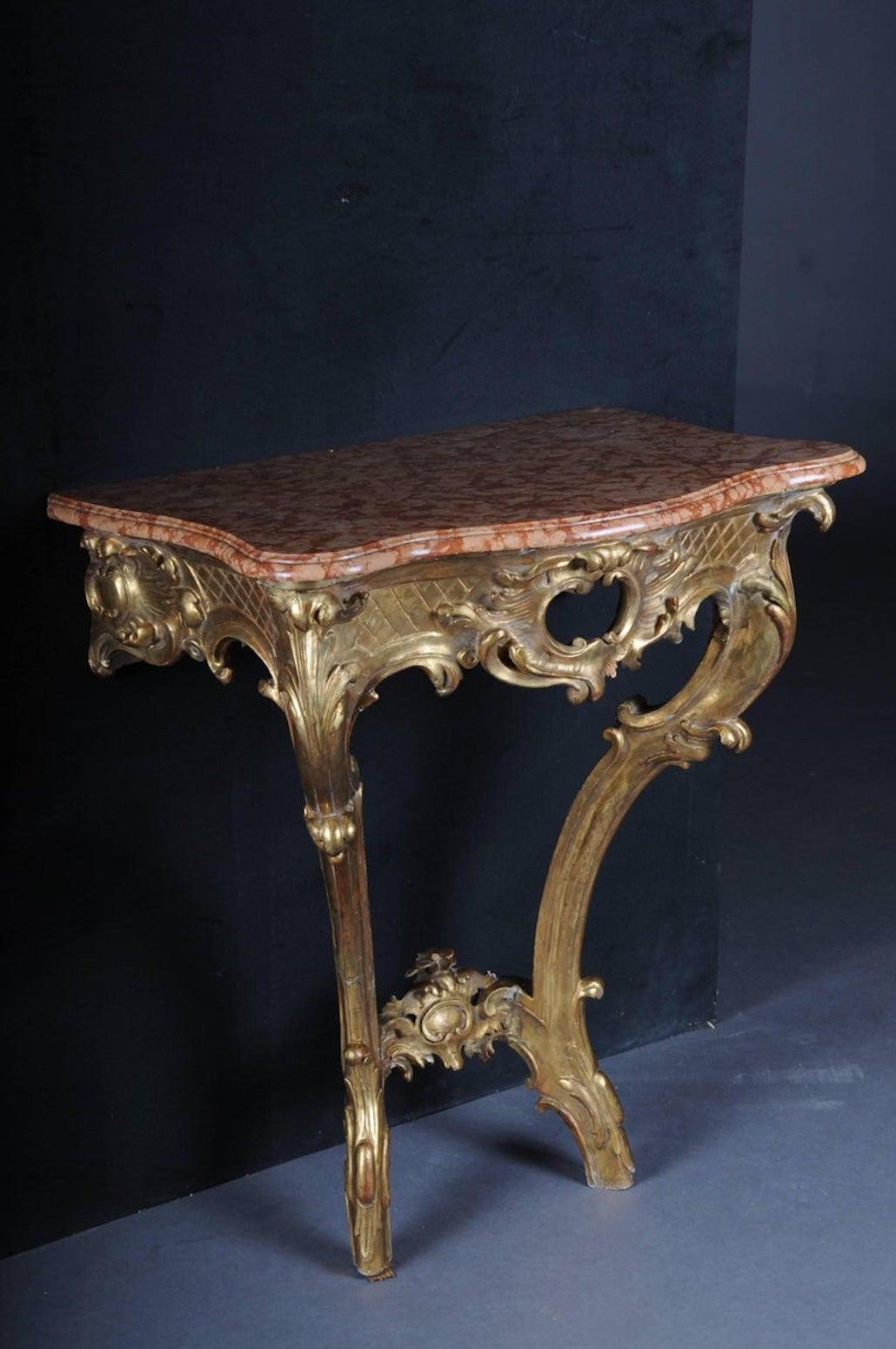 Baroque console table. Wood, gilded. Frame with openwork cartridge. Two opposing C-rocailles with bracing. Cut red marble slab. France.

