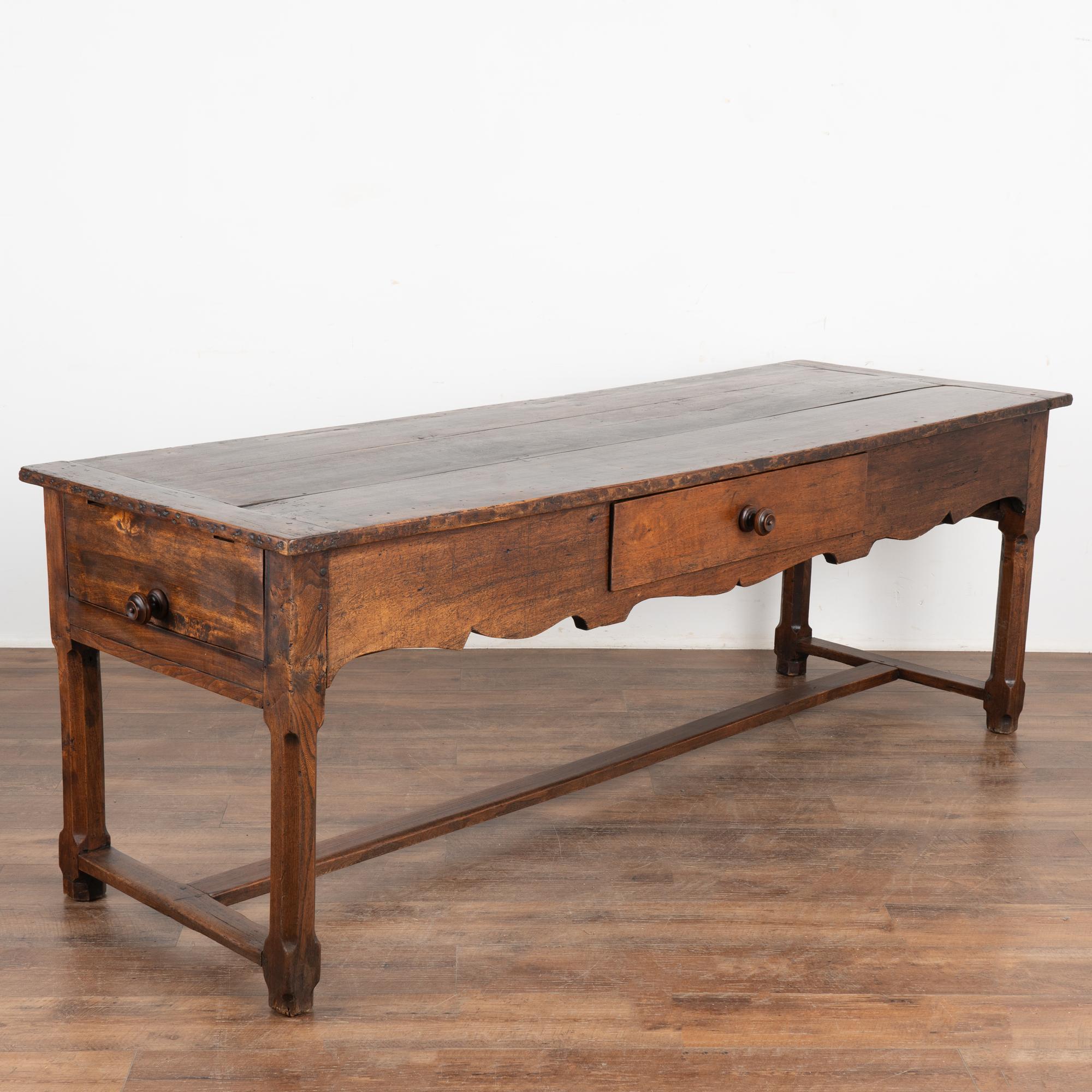 It is the stunning wood with deep aged patina that draws one to this 7' long console table from France.
The generations of use are revealed in every old knot, nick, crack, scratch and stain, etc. all resulting in the incredible patina that brings