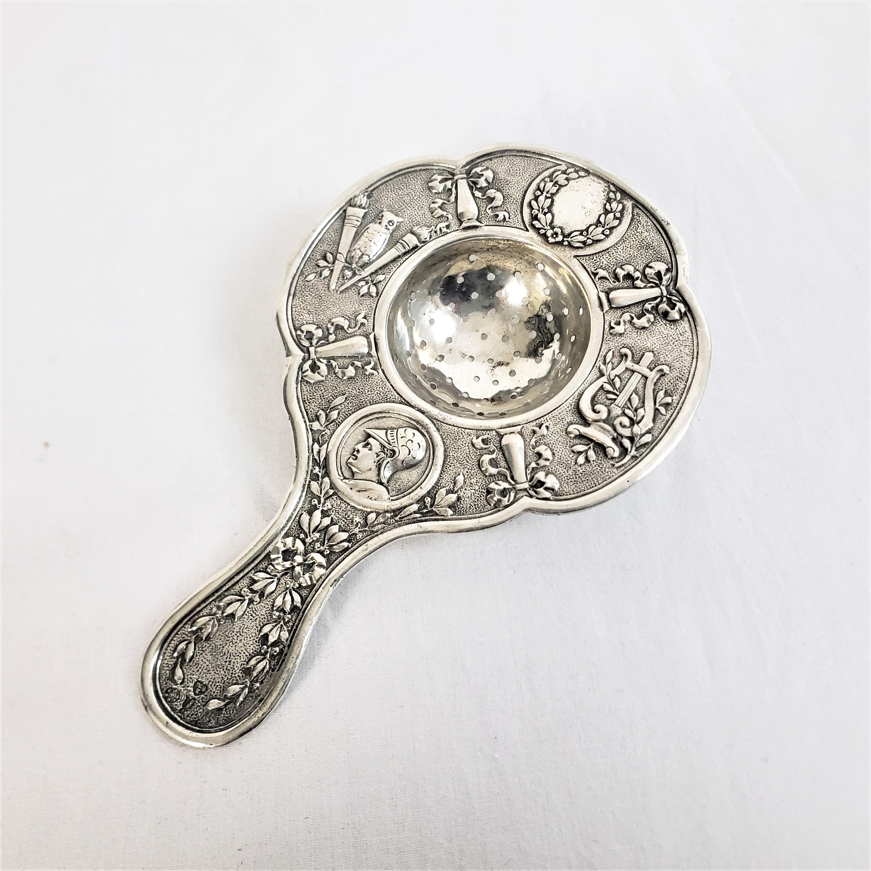 This antique tea strainer is hallmarked by an unknown maker, but originated from France and dates to approximately 1890 and done in a period Victorian style. The strainer is composed of Continental or .800 plus silver and is decorated with a raised