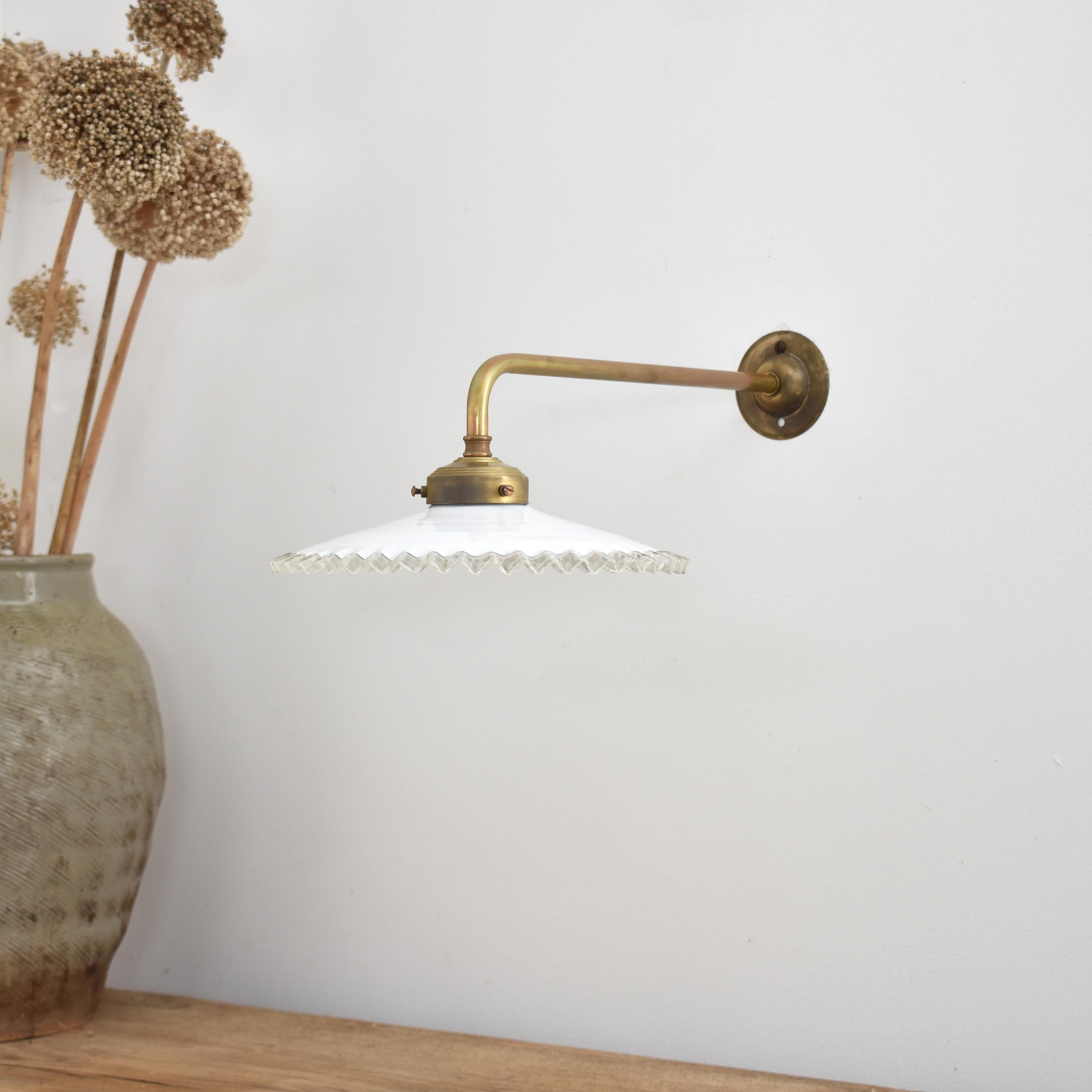 Eine frühe französische Glaskrause für die Kühlung. Der Schirm ist handgefertigt aus undurchsichtigem Glas mit einem klaren, gefalteten Rand. Die Leuchte hat eine gealterte Messinggalerie und eine Wandhalterung. Ideal als Arbeitsleuchte in der Küche