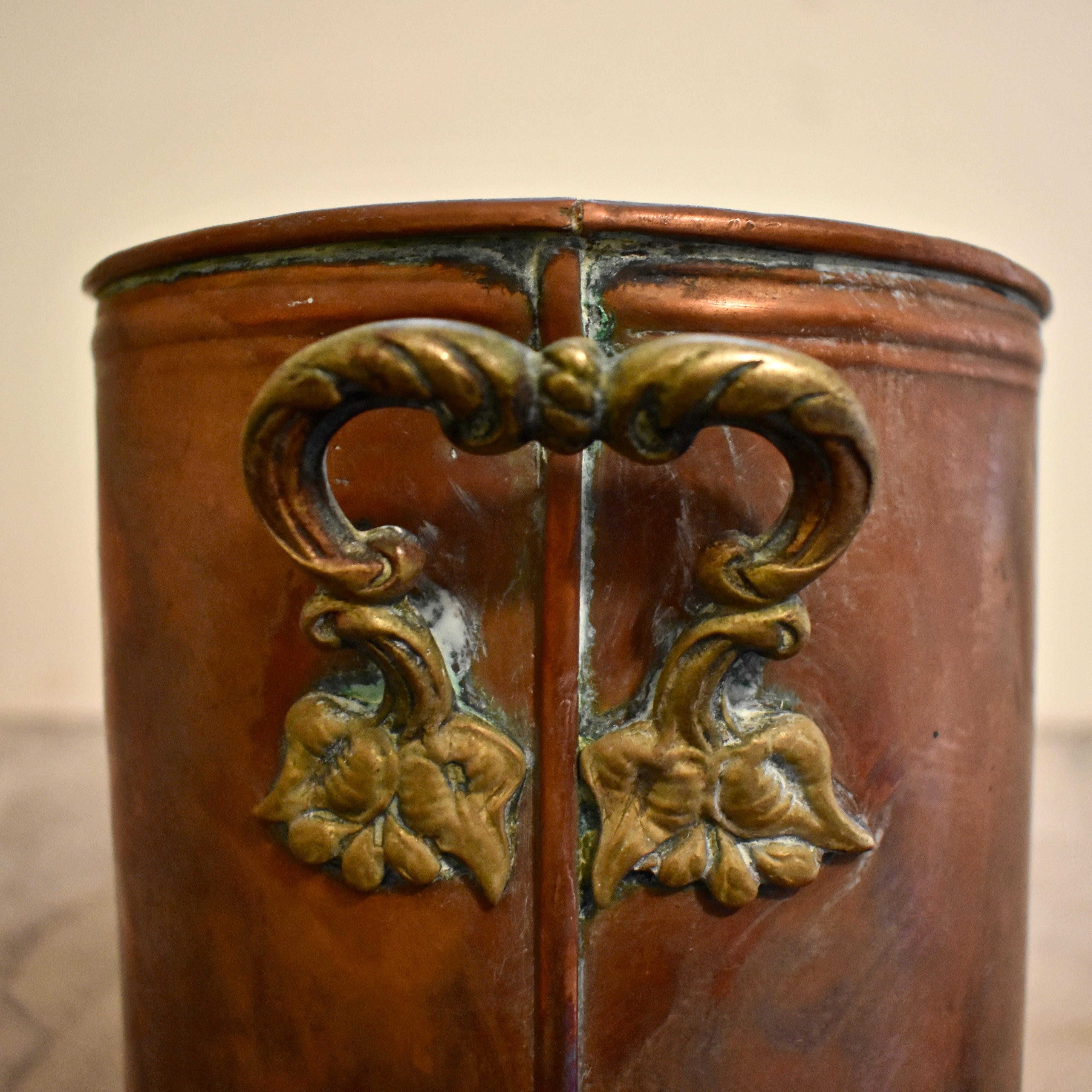 A long and heavy antique French copper potted plant holder, with a beautiful rich patina, circa early 1900s.

 Four round openings meant to hold terracotta pots, are cut into the top. The holder has rounded ends showing ornate floral brass side