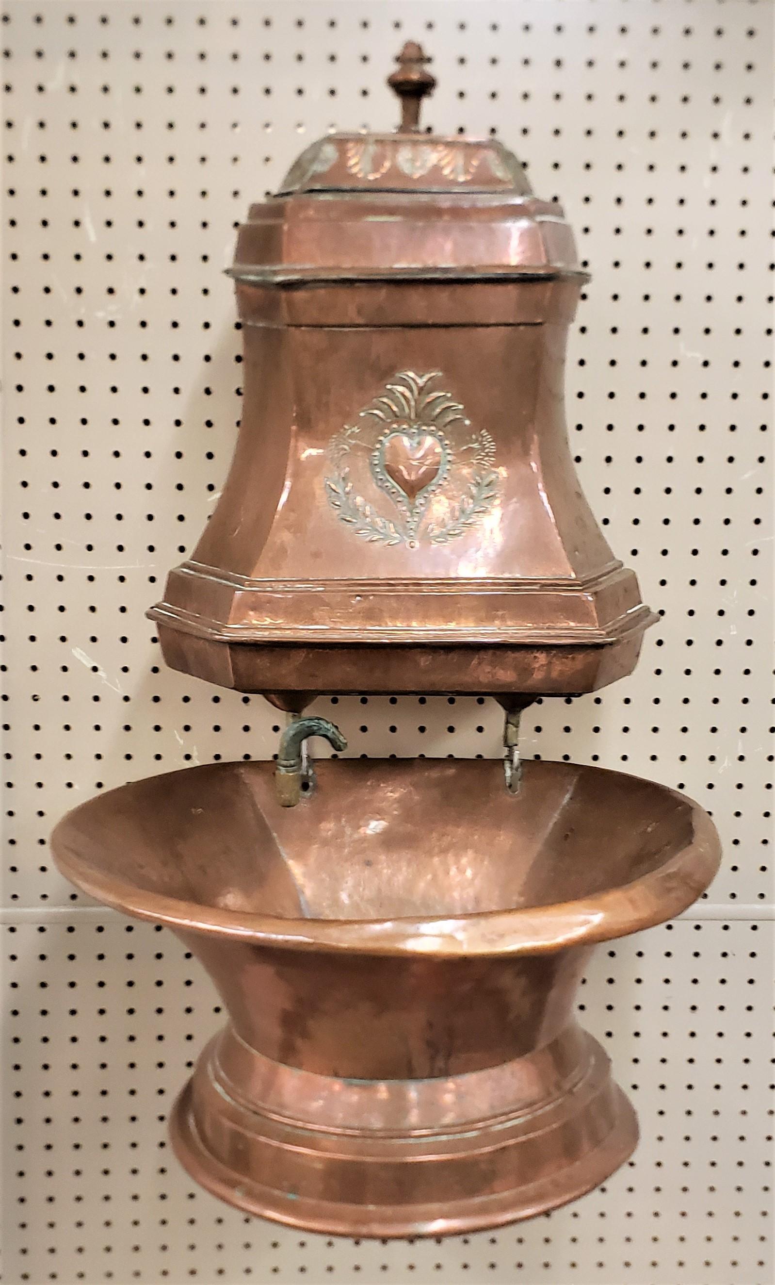 This antique copper lavabo or cistern and sink is unsigned, but presumed to originate from France and date to approximately 1890 and done in the period French Provincial style. The six sided cistern is ornately decorated with a contoured top with