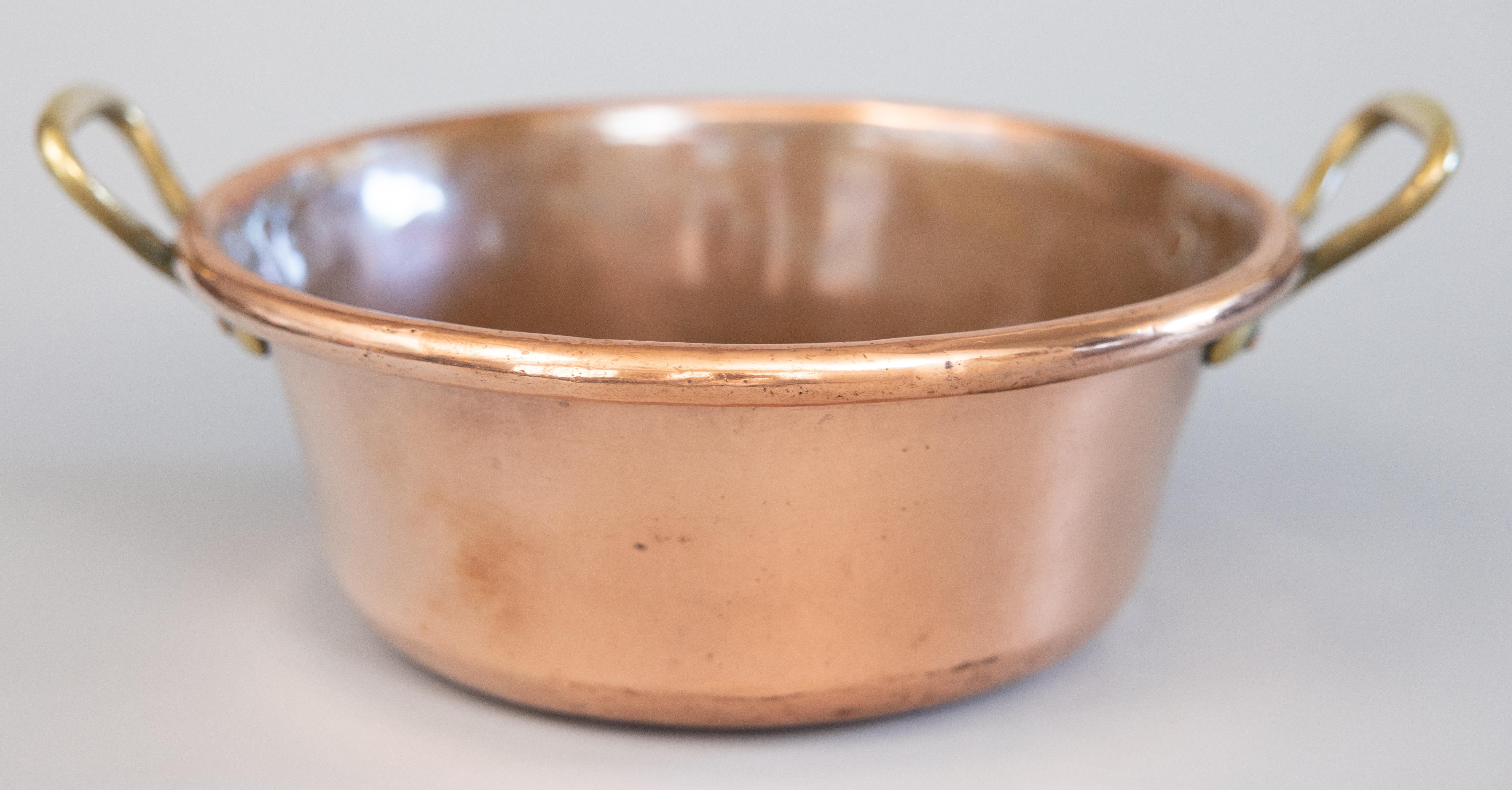 A gorgeous antique hand forged French copper pot, circa 1900. This fine pot is handcrafted of solid copper, large and heavy, with charming brass handles and a beautiful patina. It would be lovely displayed on its own, filled with decorative items,